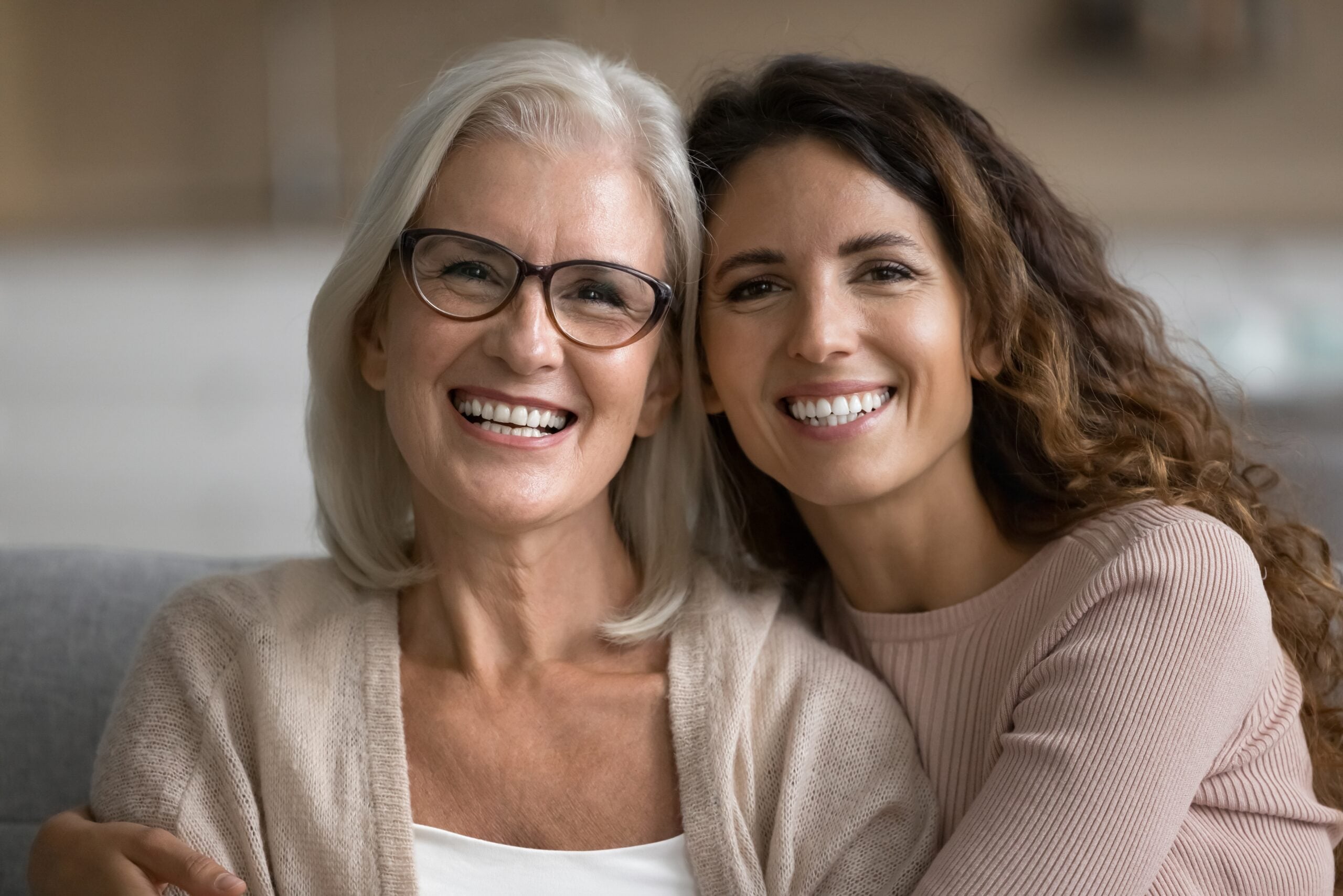 Mother and her adult daughter sitting together and looking happy.
