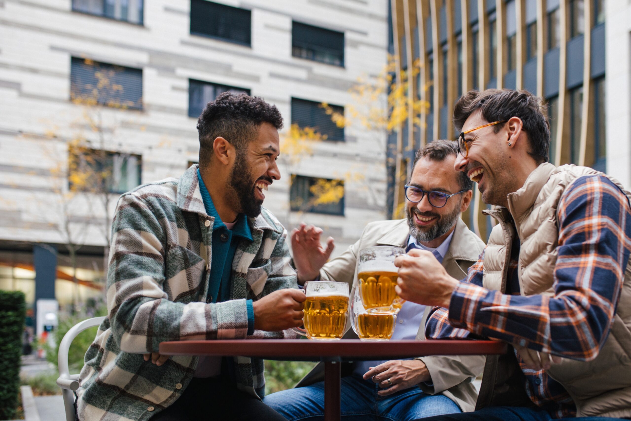 Three male friends joking around with one another over beers.