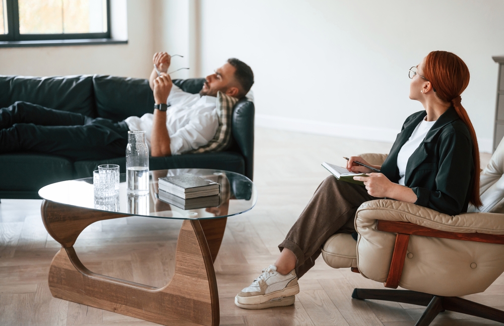 A man in therapy, talking to his therapist while lying on the couch