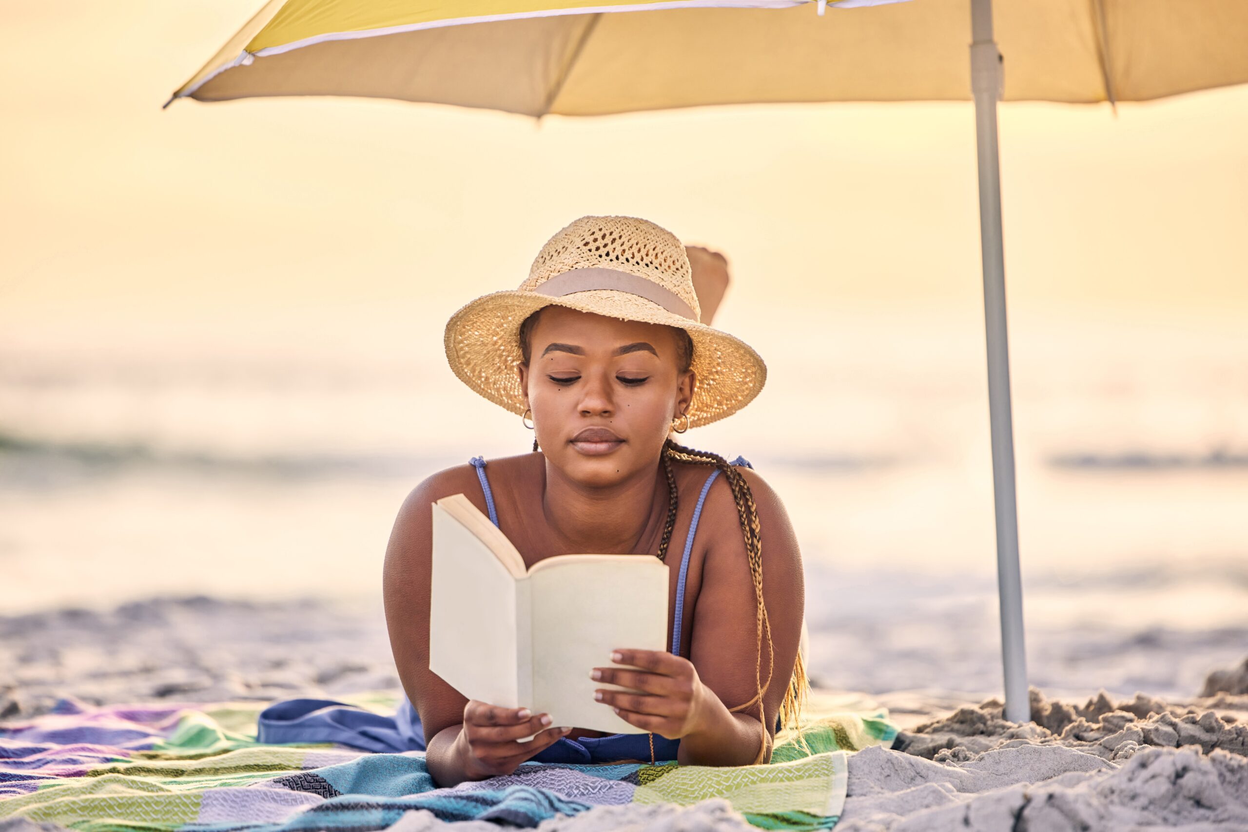 Woman spending time alone reading on the beach.