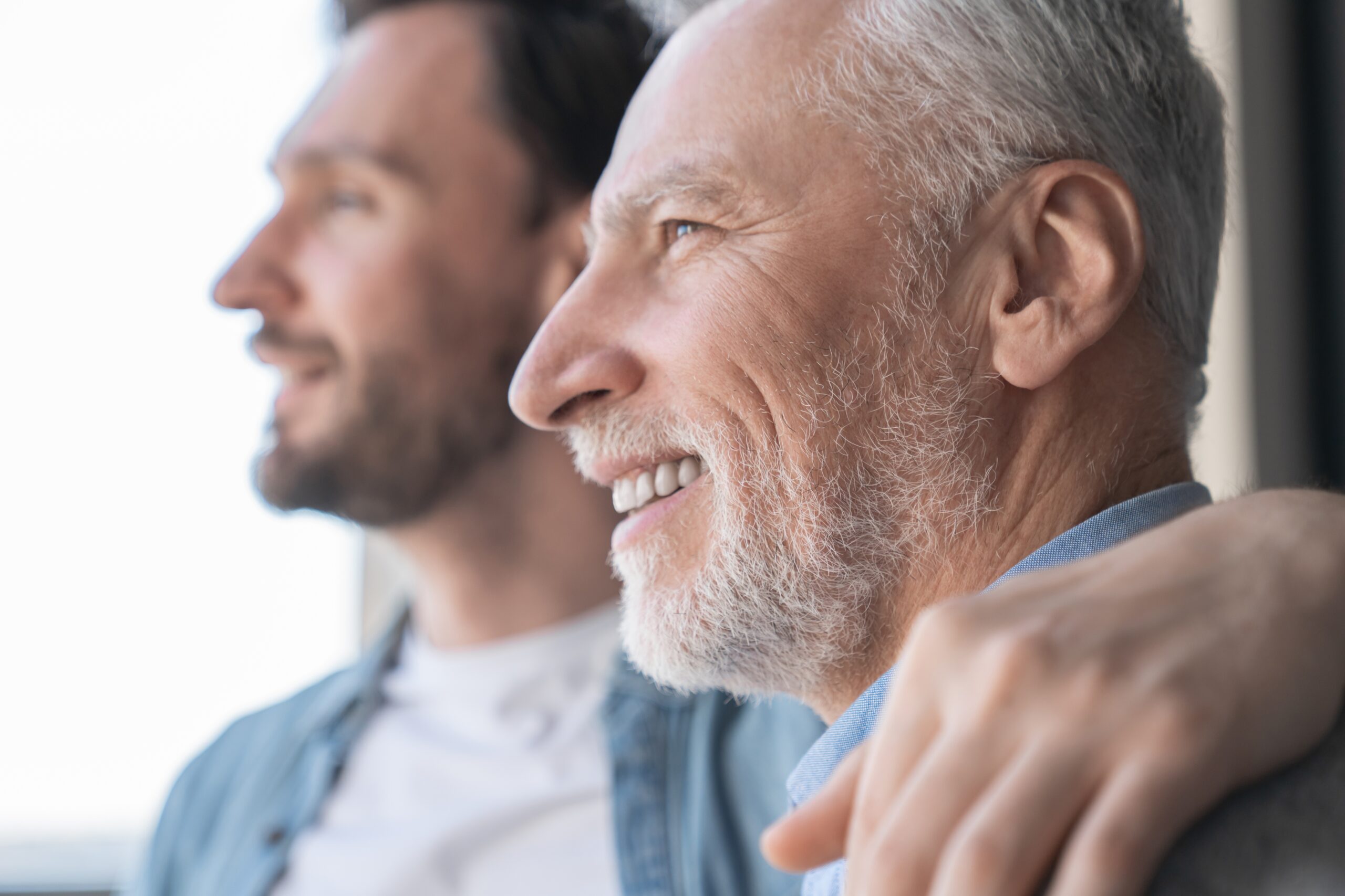 Adult son with his arm wrapped around his father's shoulder.