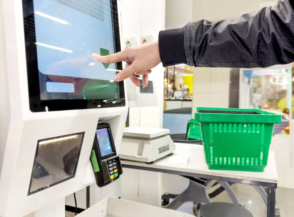 Someone at the self checkout in a supermarket, paying for his purchases