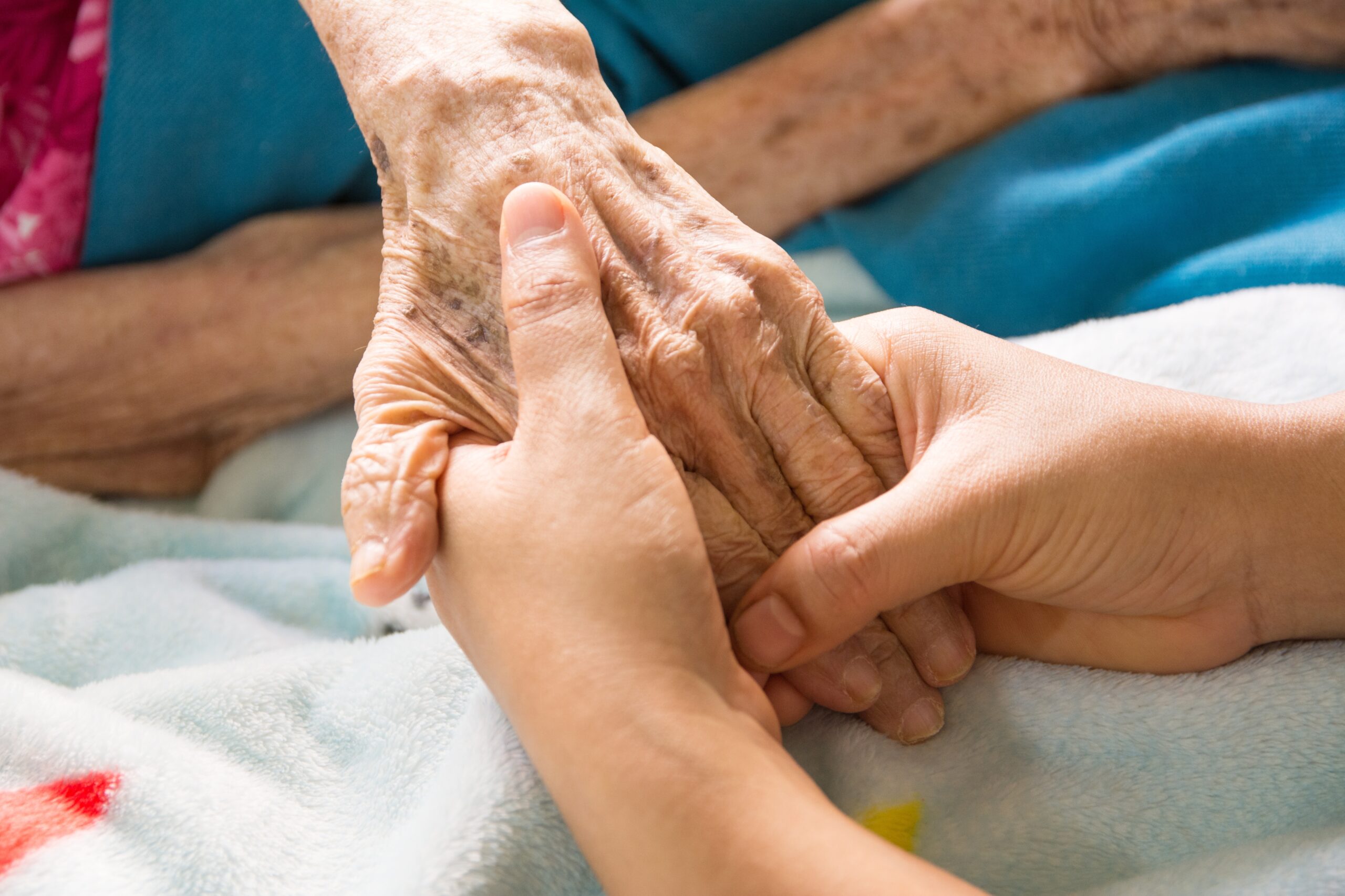 Close up young woman's hand holding an old woman's hand.