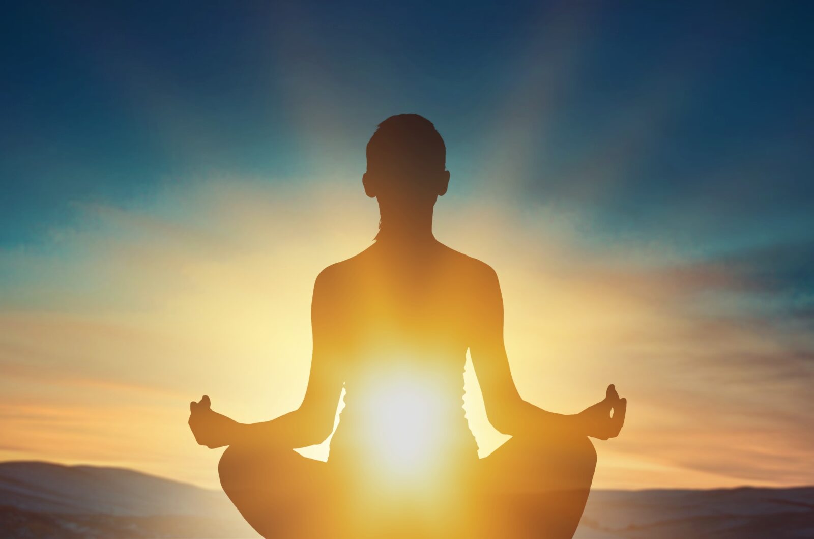 Young woman meditating at sunset.