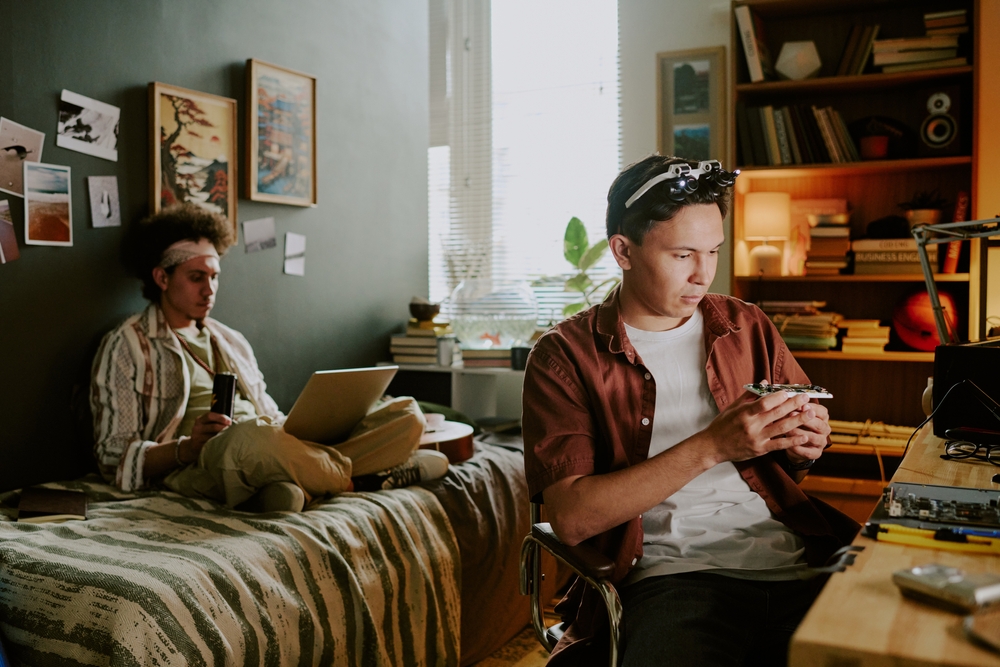 Two male roommates together in their room and working on separate things