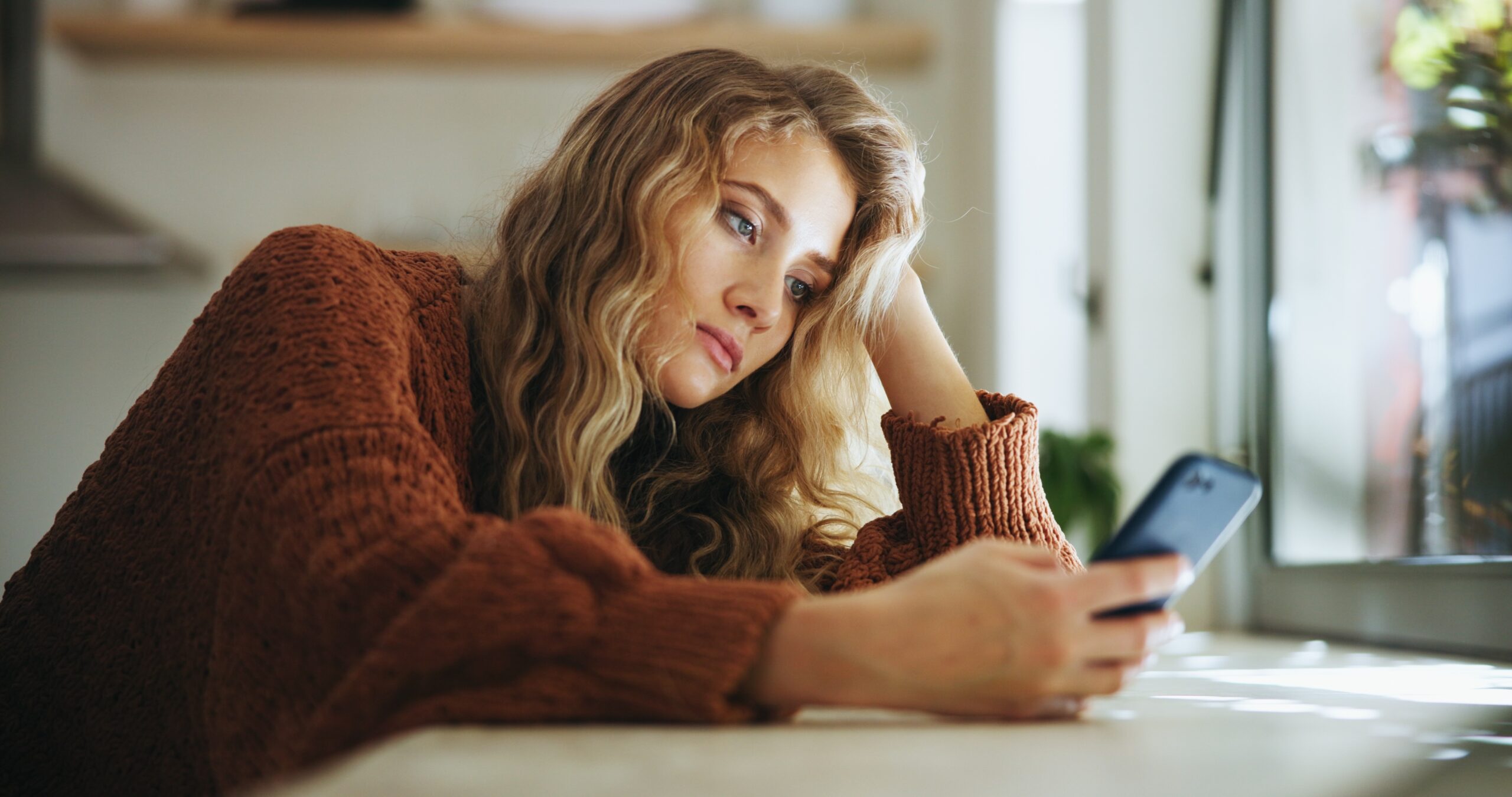 A woman feeling isolated and looking at her phone.