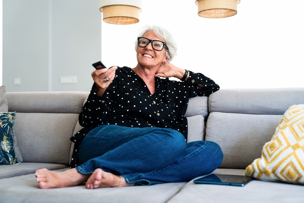 A senior woman watching TV and smiling. 