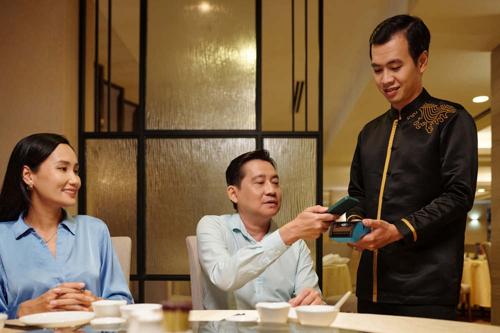 A man paying the restaurant bill while out for dinner with his family.