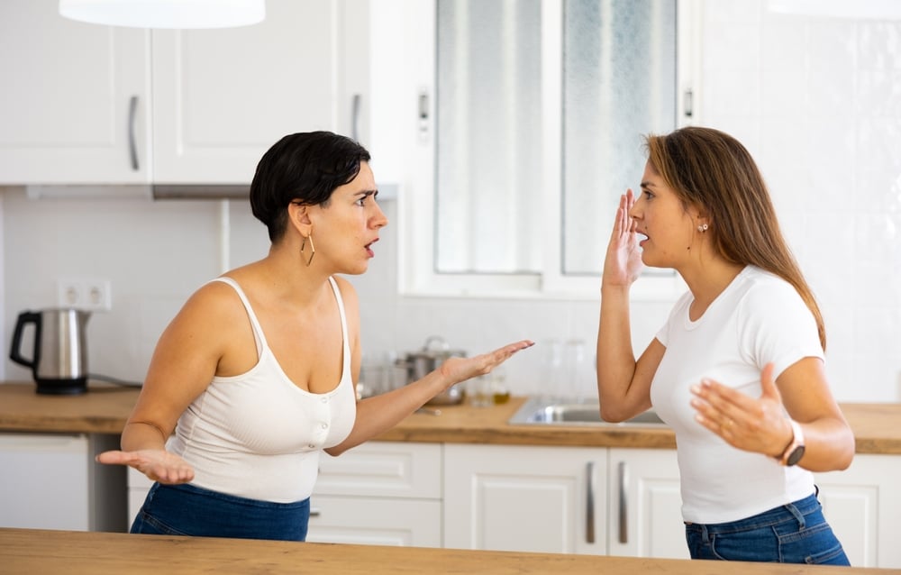 Two women having a fight and a showdown in the kitchen at home