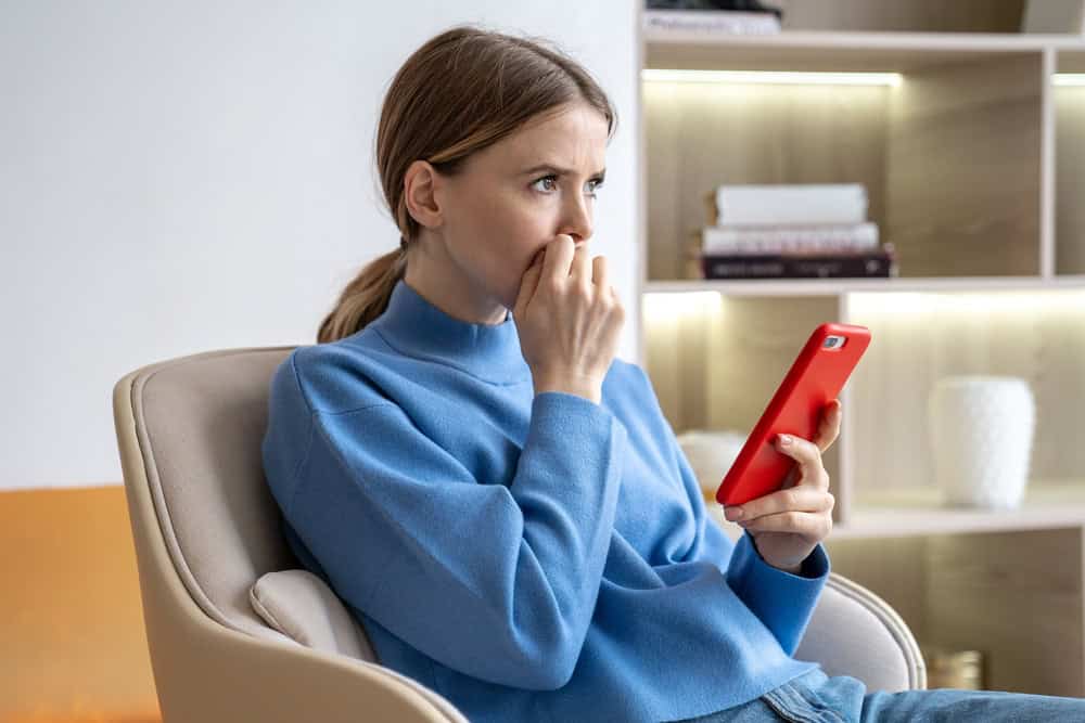A nervous, anxious woman sitting on the couch in her living room and thinking