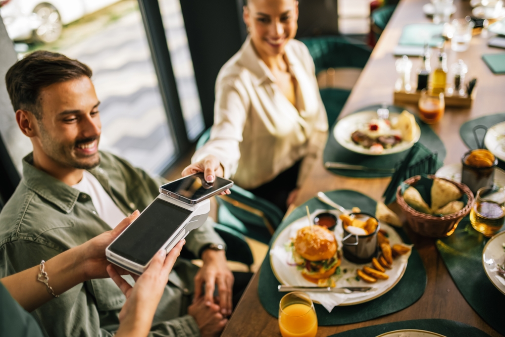 A young woman paying the dinner bill on behalf of her friends