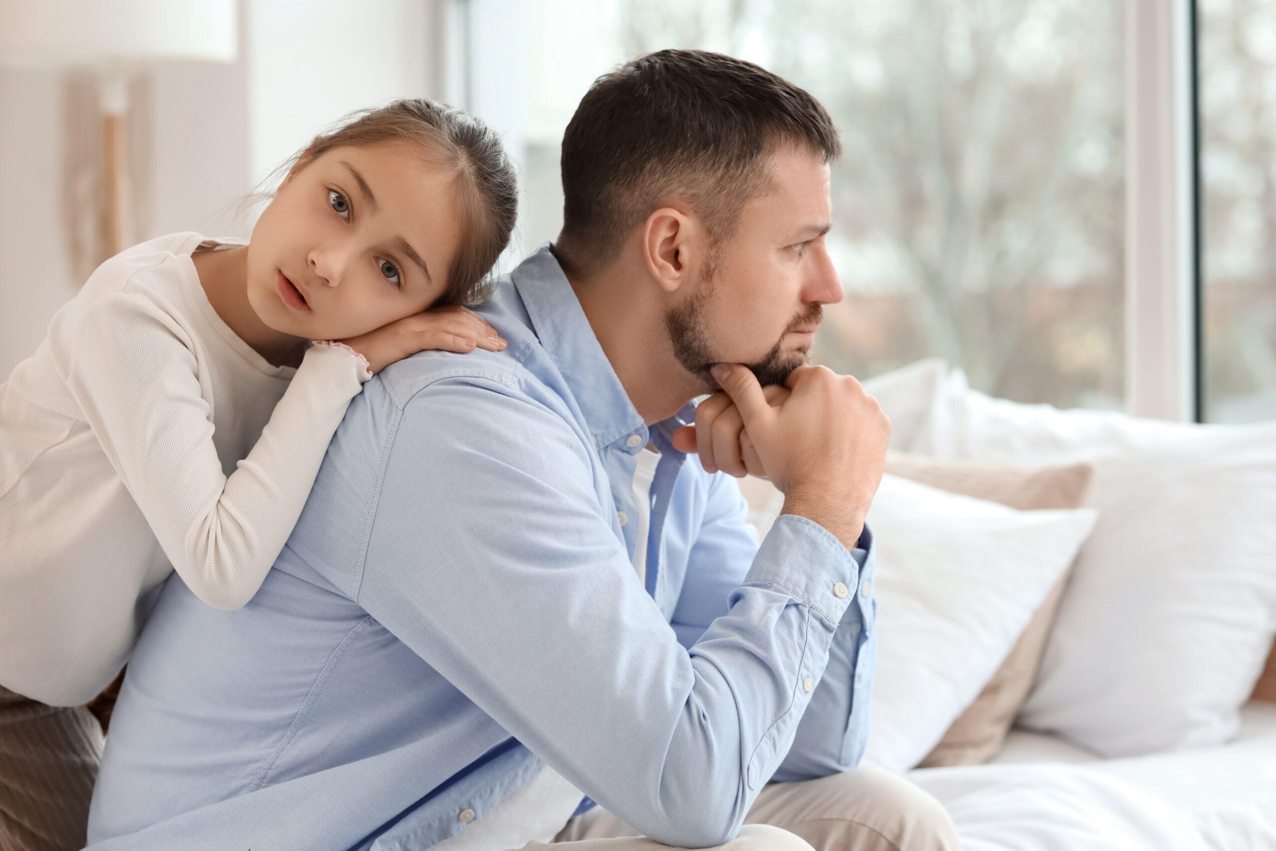 A father disappointed with his daughter and giving her the silent treatment while she lies on his back to apologize