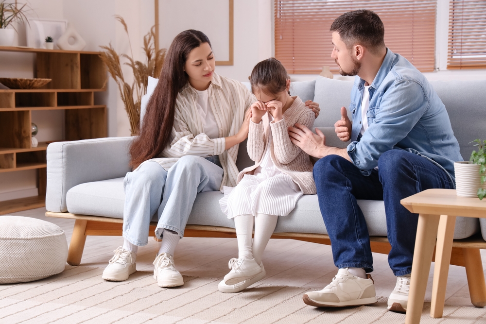 A mother and father comforting to their young daughter.