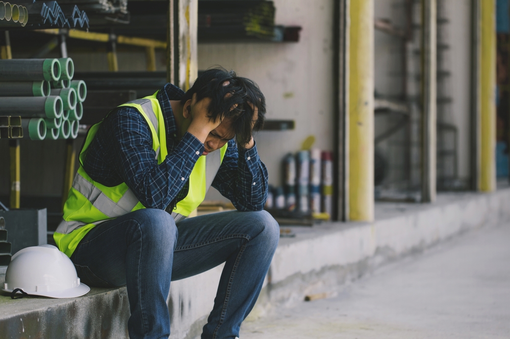 A factory worker sitting on the steps after losing his job