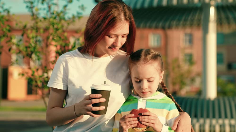 A mother and daughter eating snacks outside