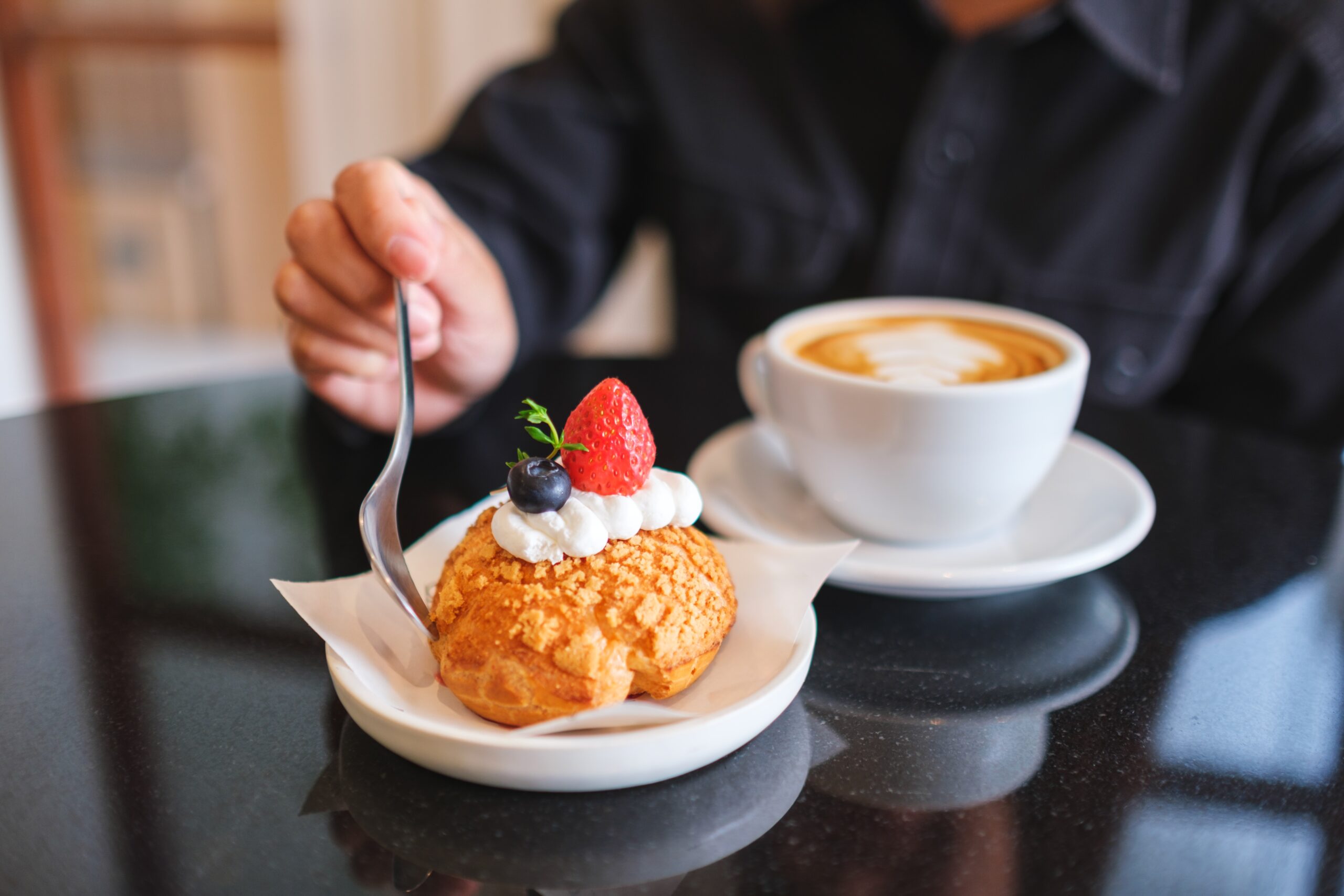 A man enjoying pastry and coffee at his local cafe.