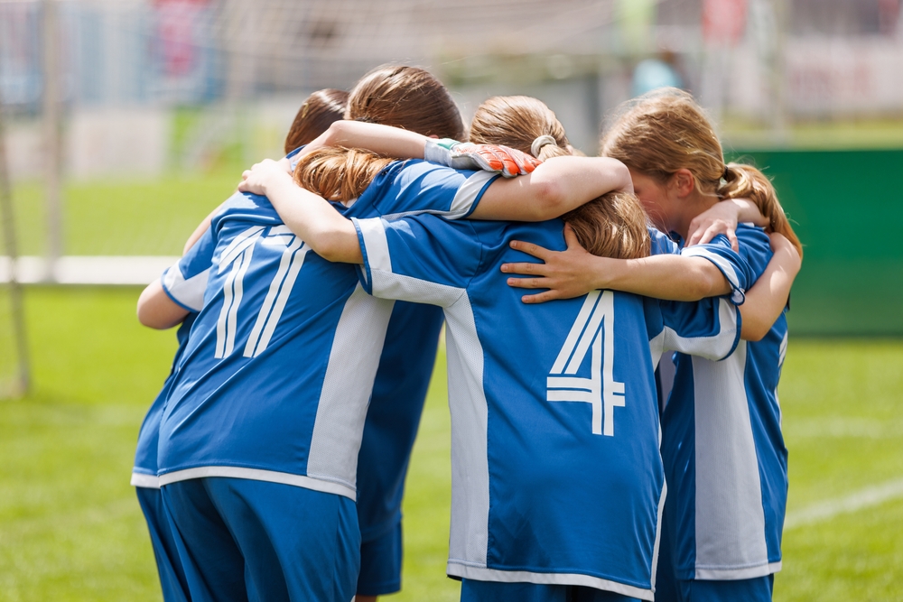 Youth girls' soccer team in a pre-game huddle.