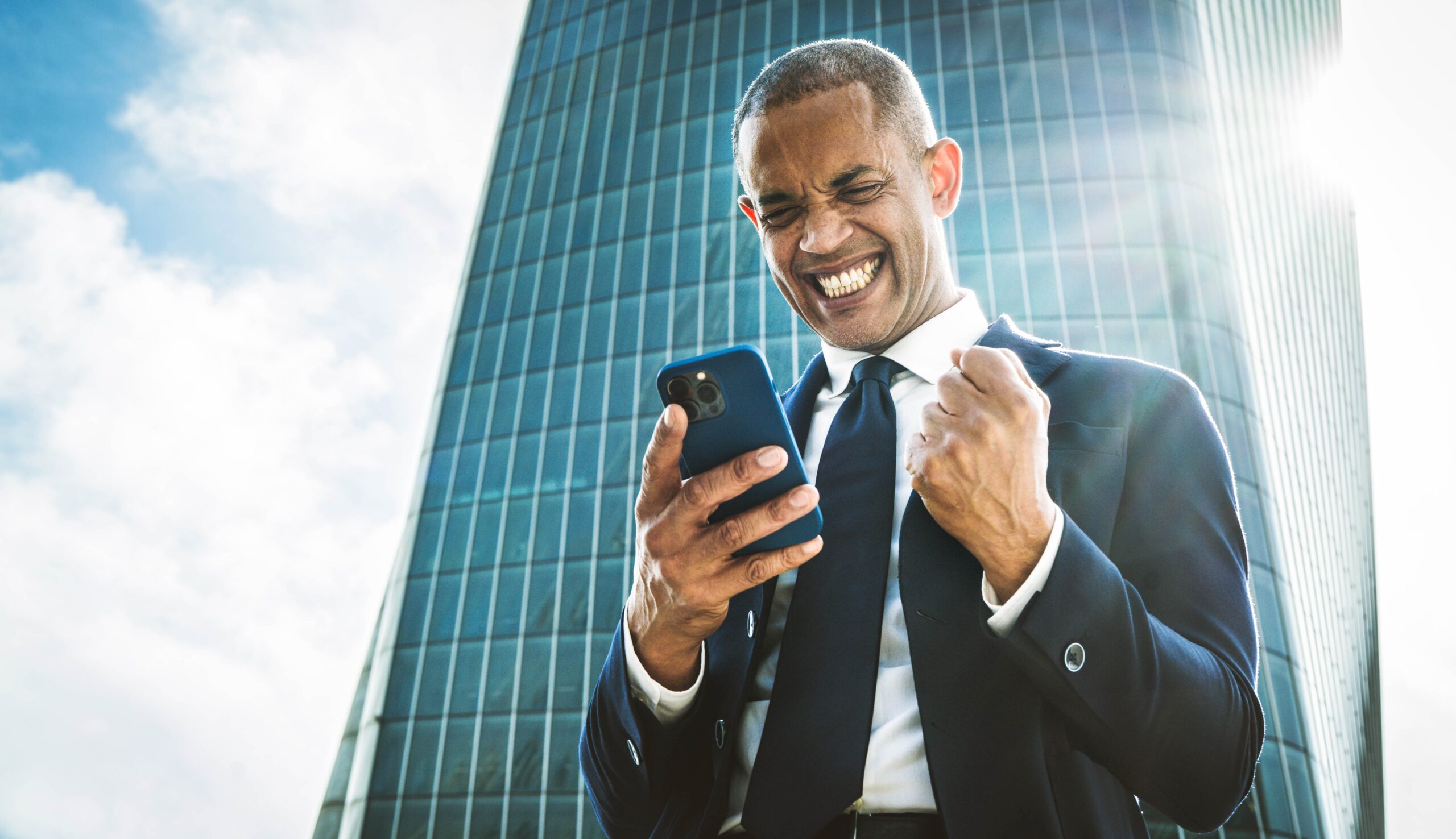 Successful businessman holding mobile phone gesturing yes.