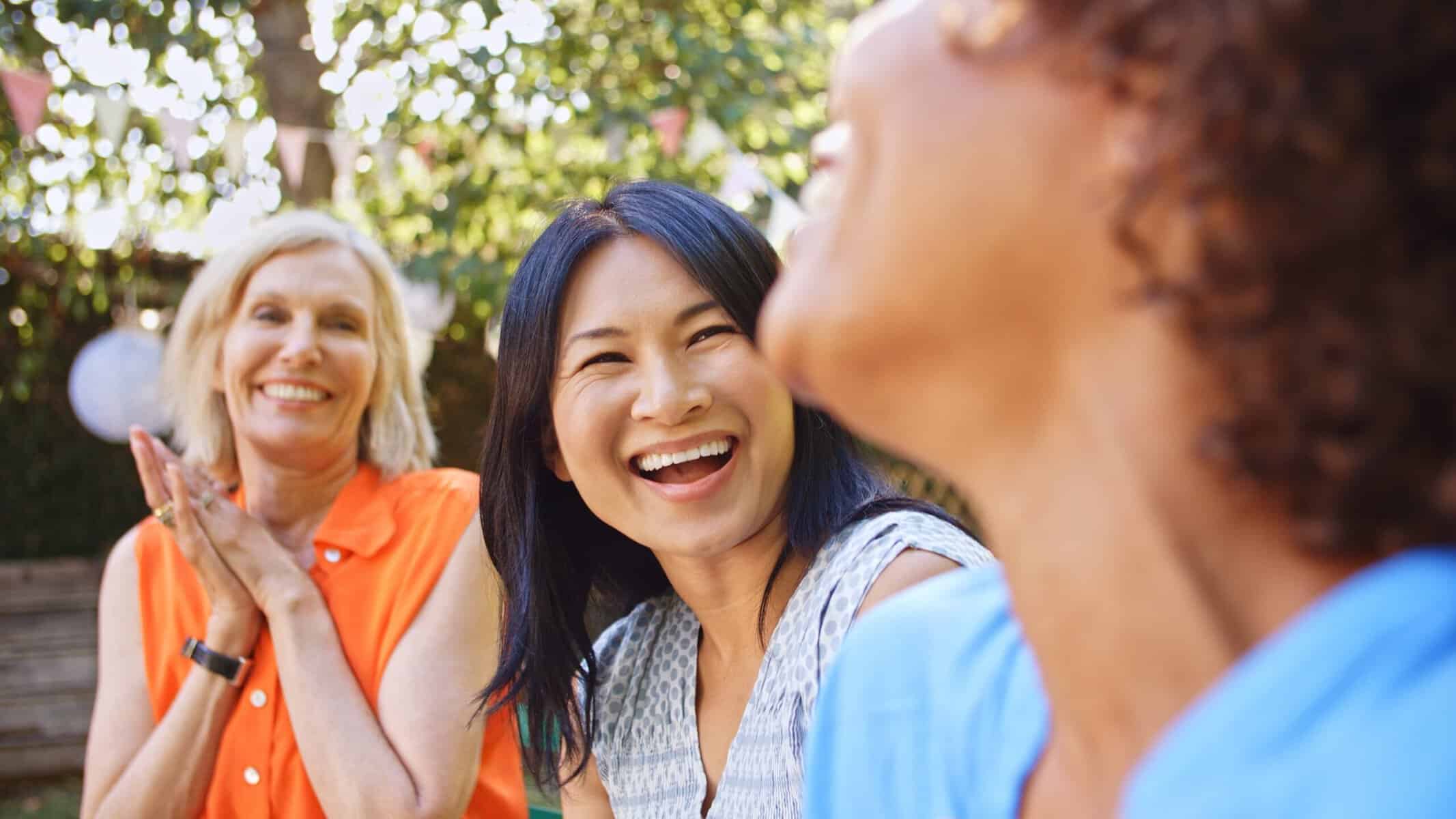 Three adult friends enjoying one another's company at an outdoor gathering.