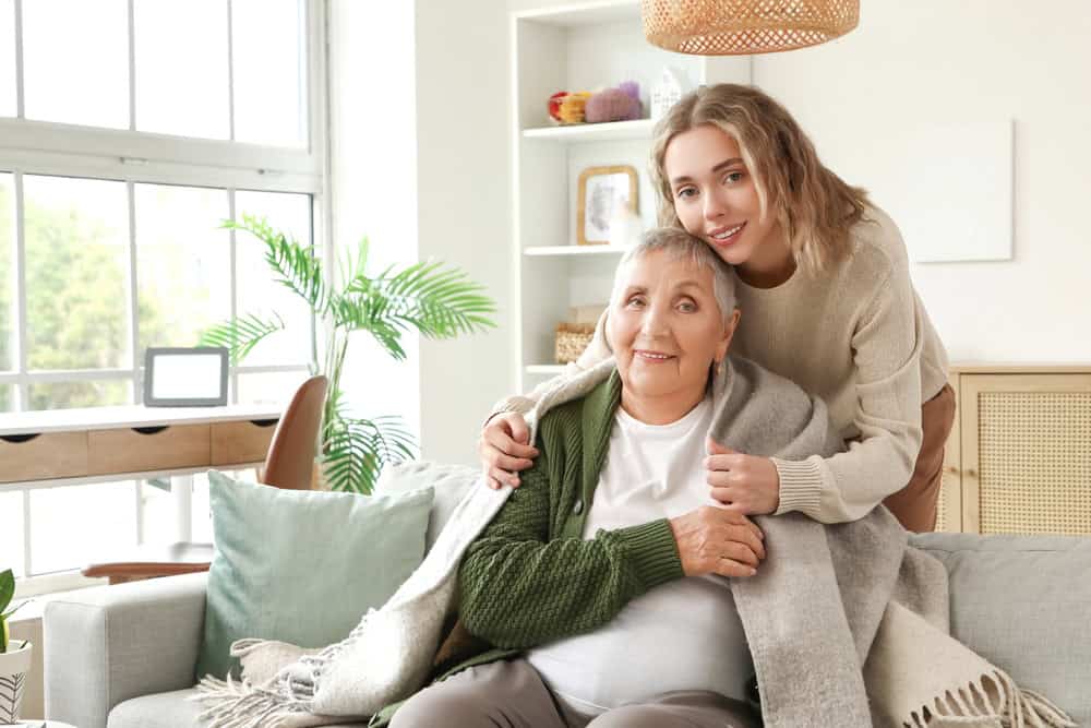 A young granddaughter hugging her proud grandmother and covering her with a blanket.