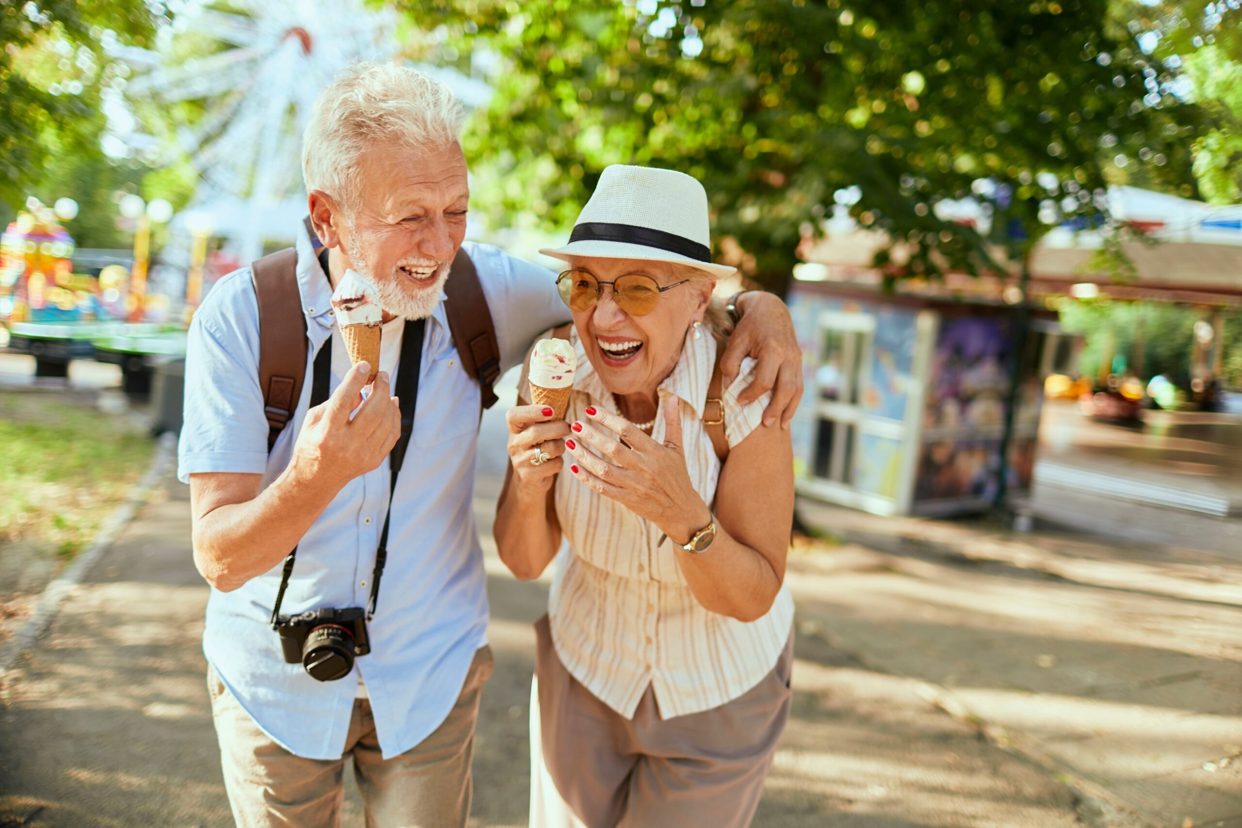 A senior couple eating ice cream and laughing together.