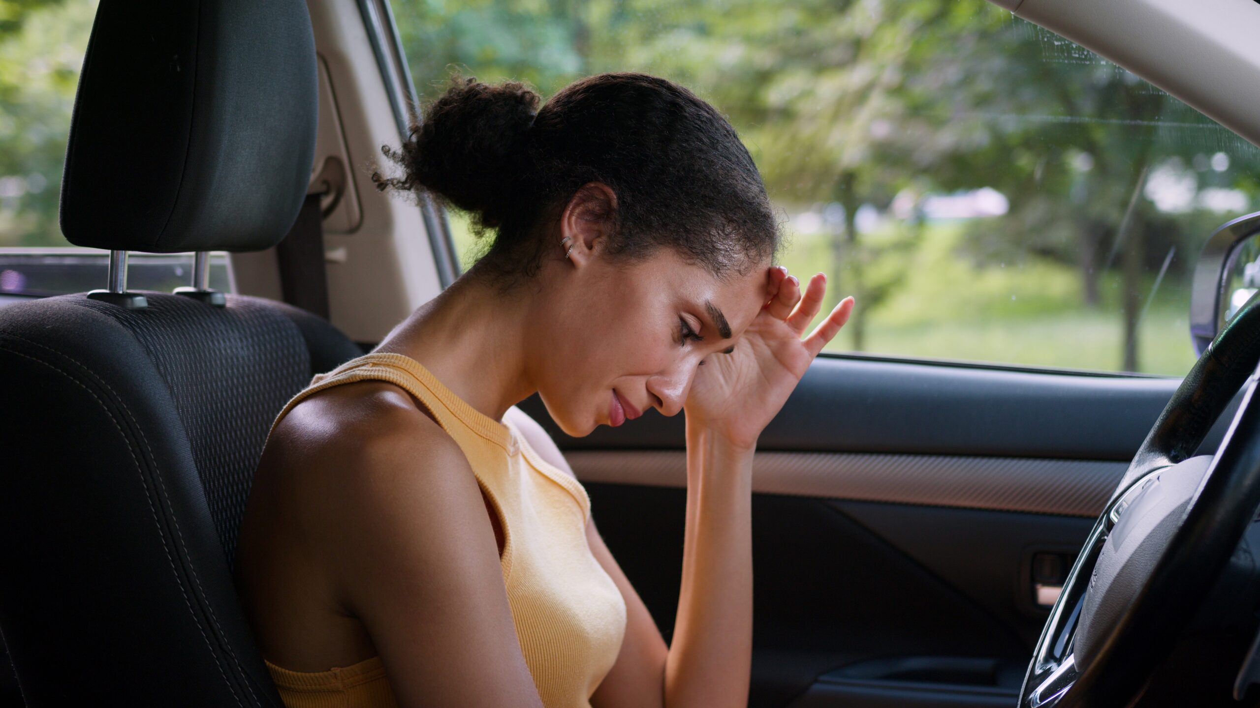 An overwhelmed woman sitting in her car.