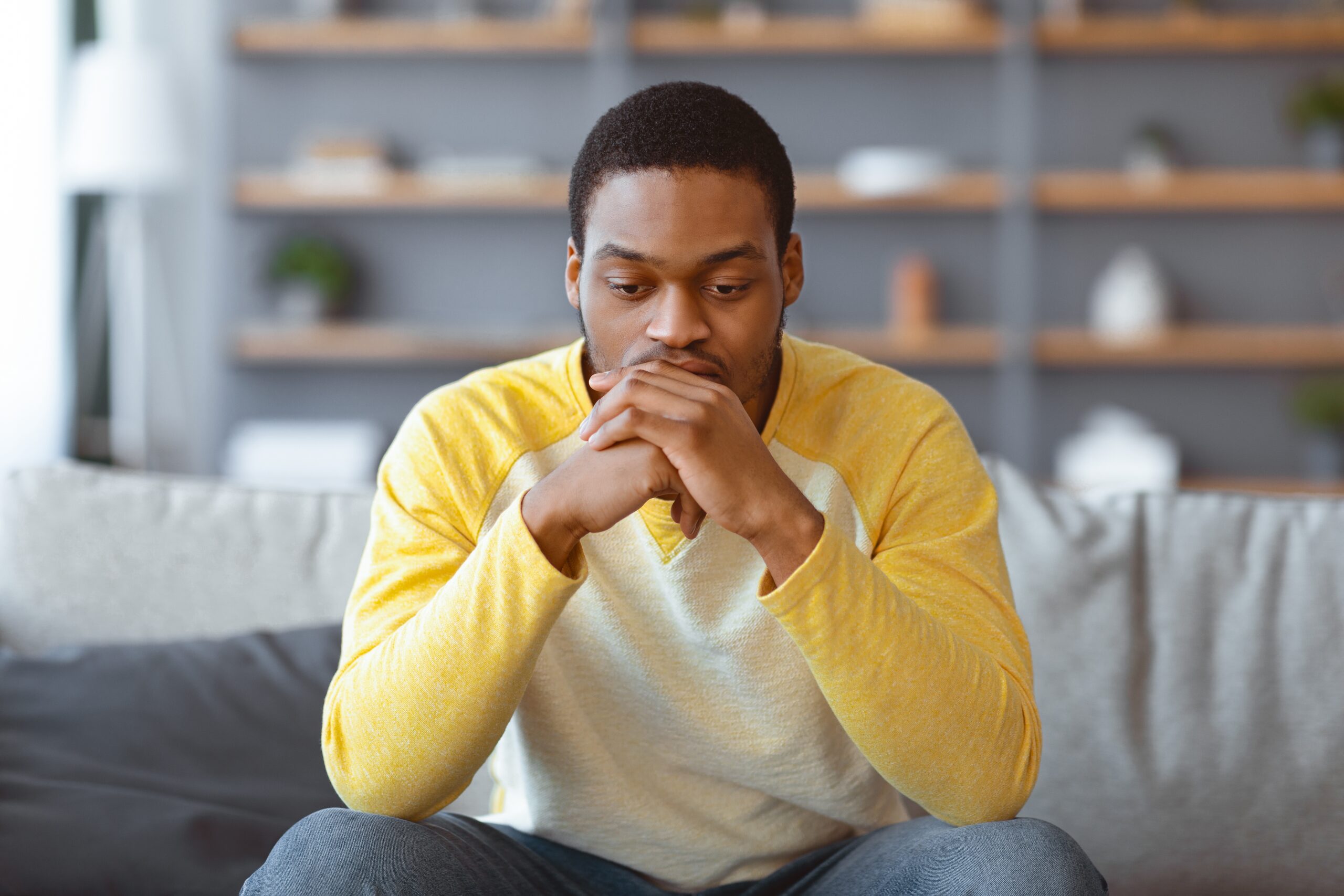 A joyless man sitting alone and thinking.