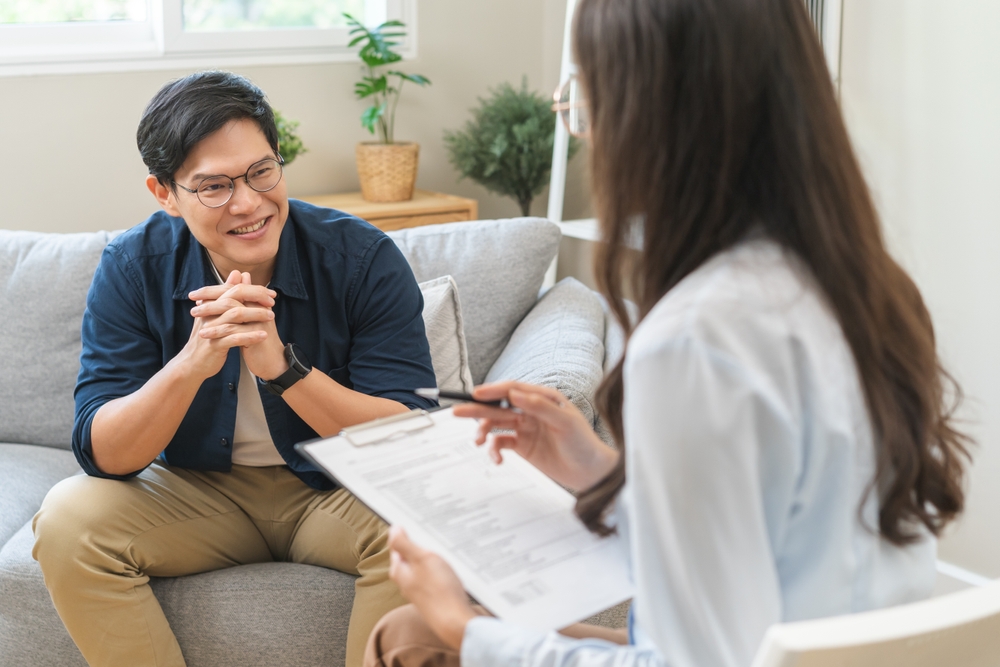 An Asian man in therapy, smiling at his therapist