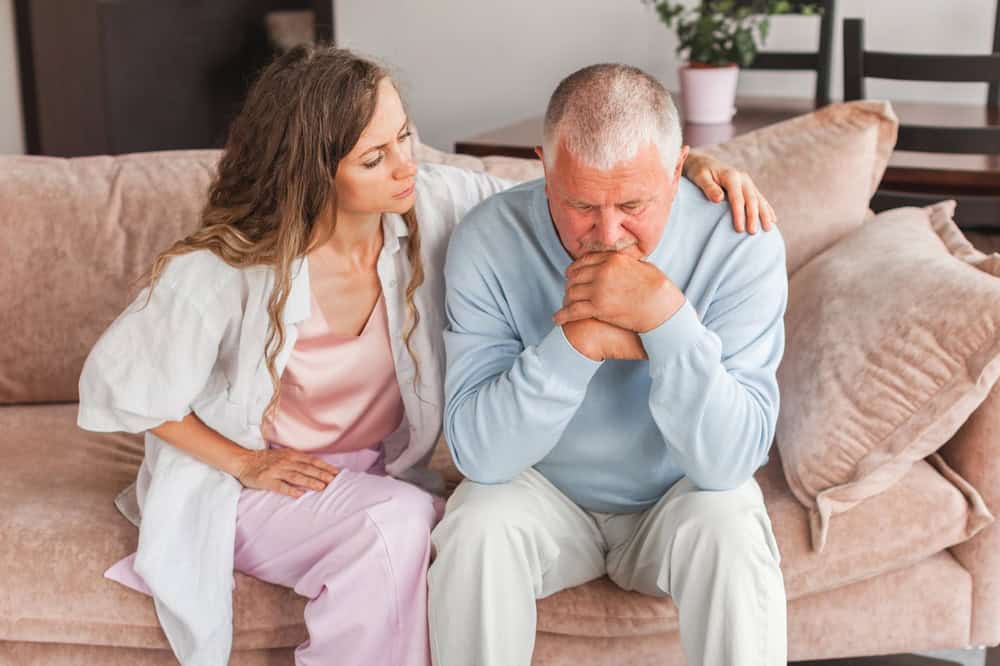 A loving adult daughter consoling her senior father.