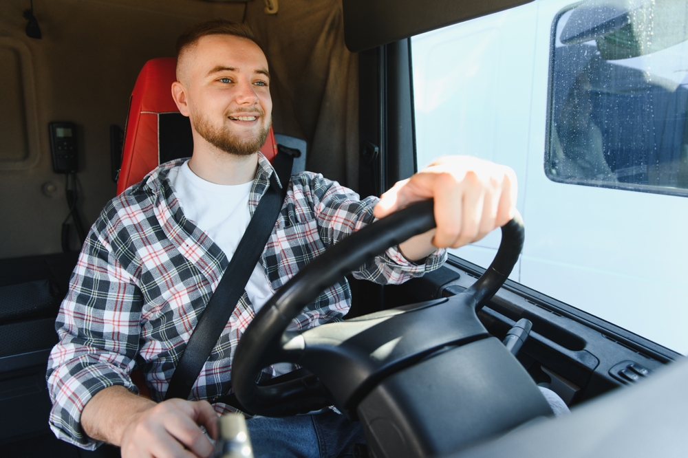 A young male truck driver smiling as he drives