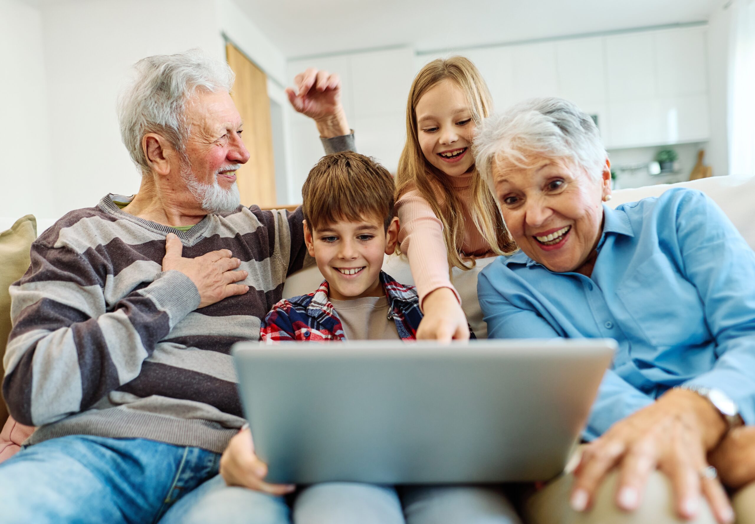 Two grandchildren watching a video with their beloved grandparents.
