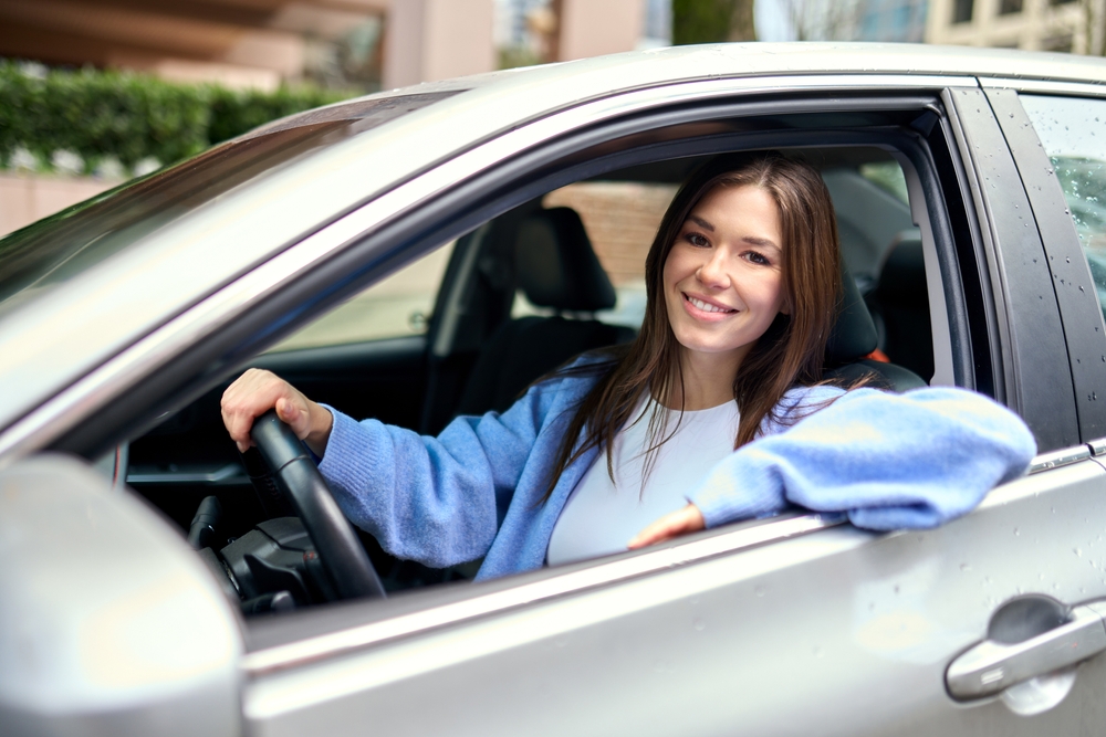 A happy young woman driving her car