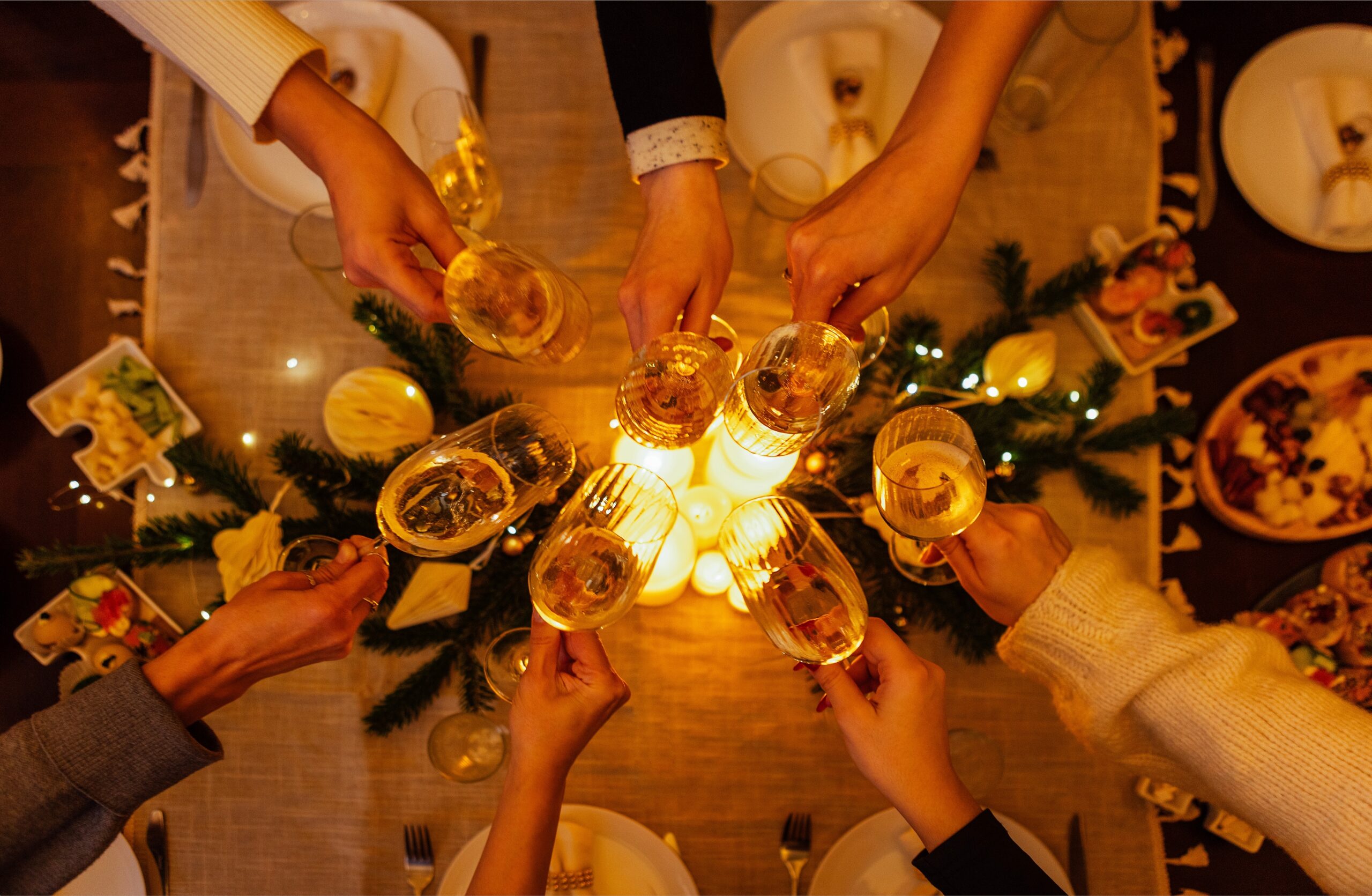 Wealthy family dinner with female and male hands holding elegant glasses of champagne.