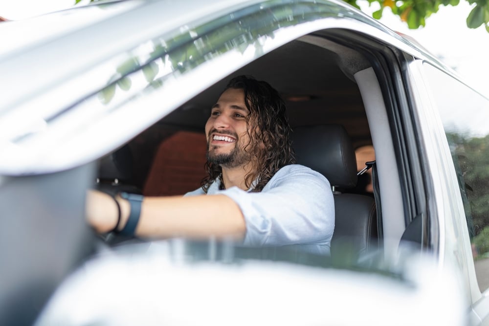 A smiling happy LGBTQ man driving his car