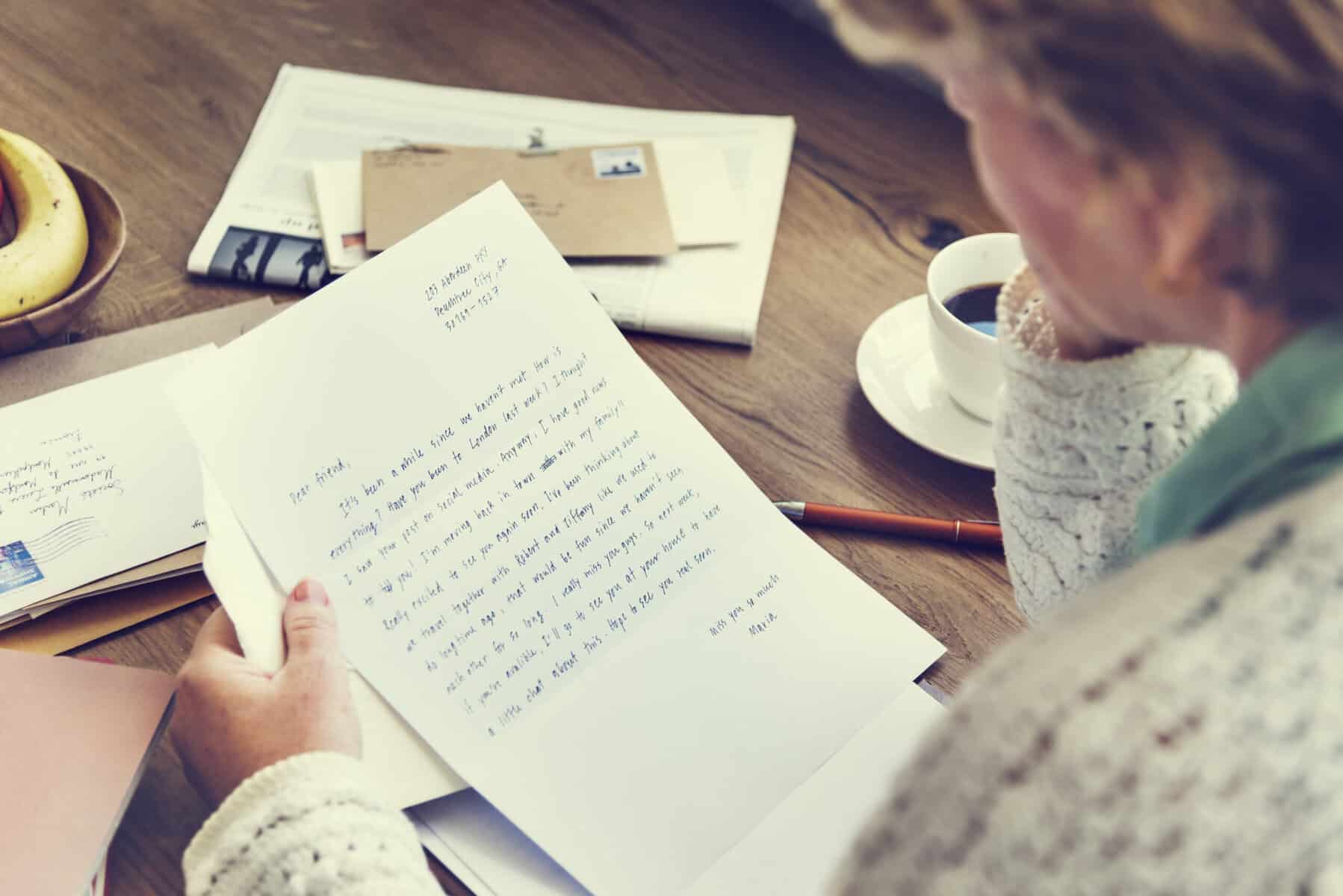 A mature woman reading a hand written letter that arrived via the mail.