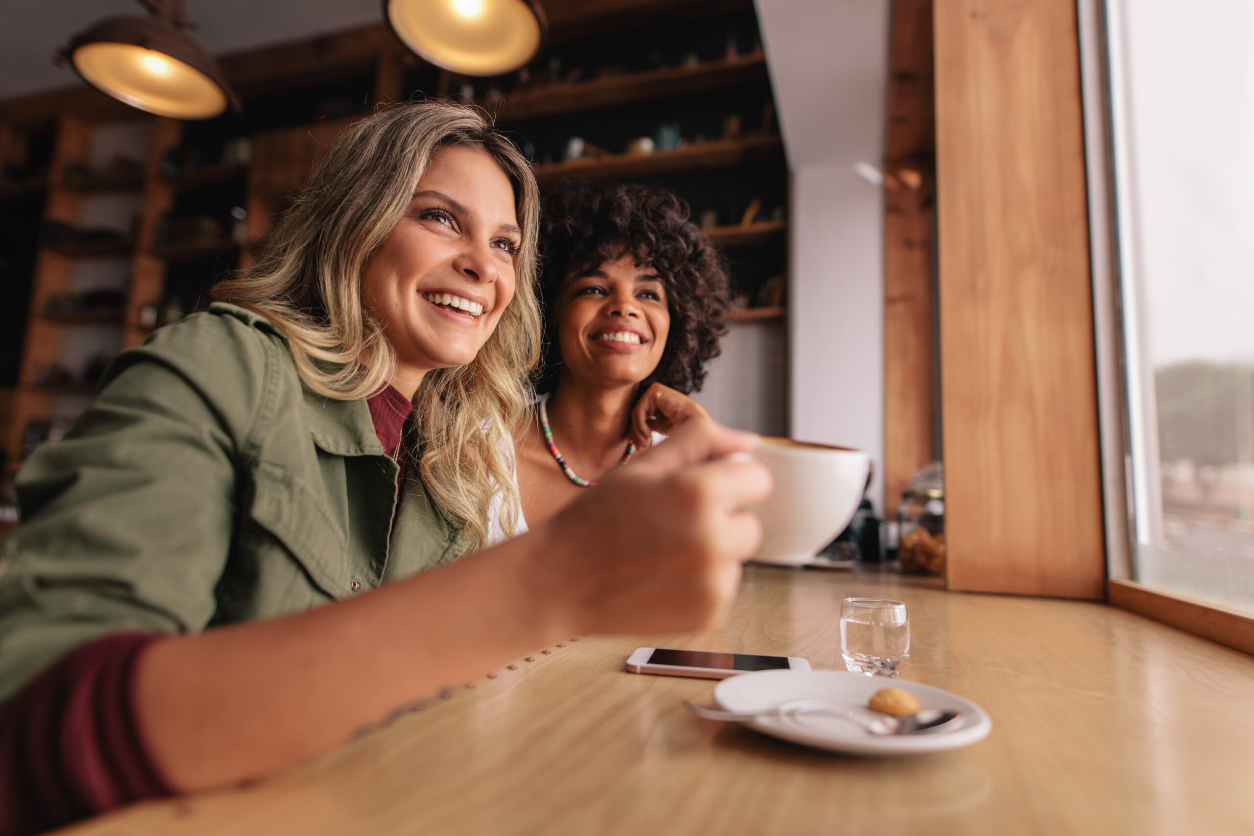 Two female friends catching up over coffee together at a cafe.