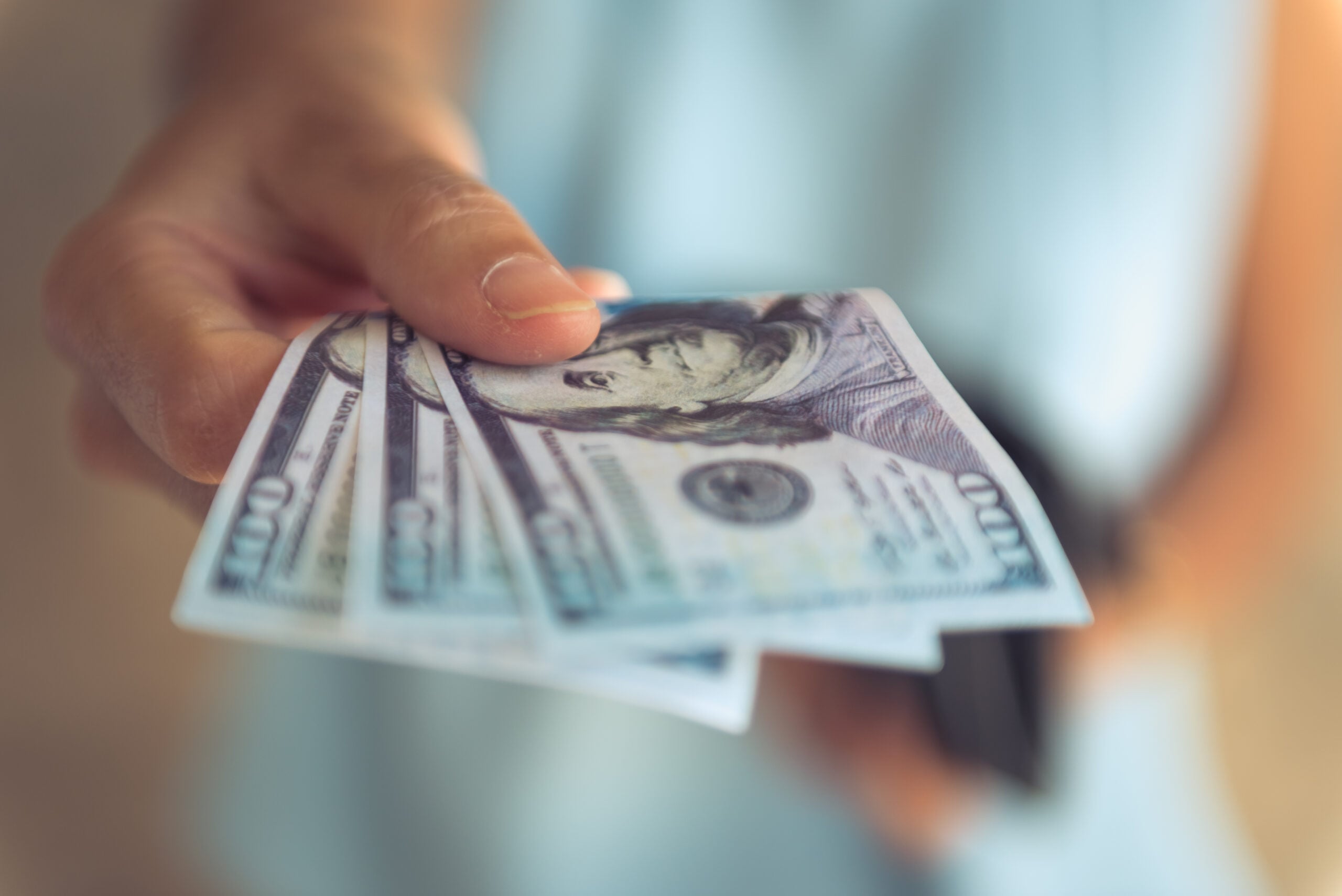 A woman is using cash to pay for her bill.