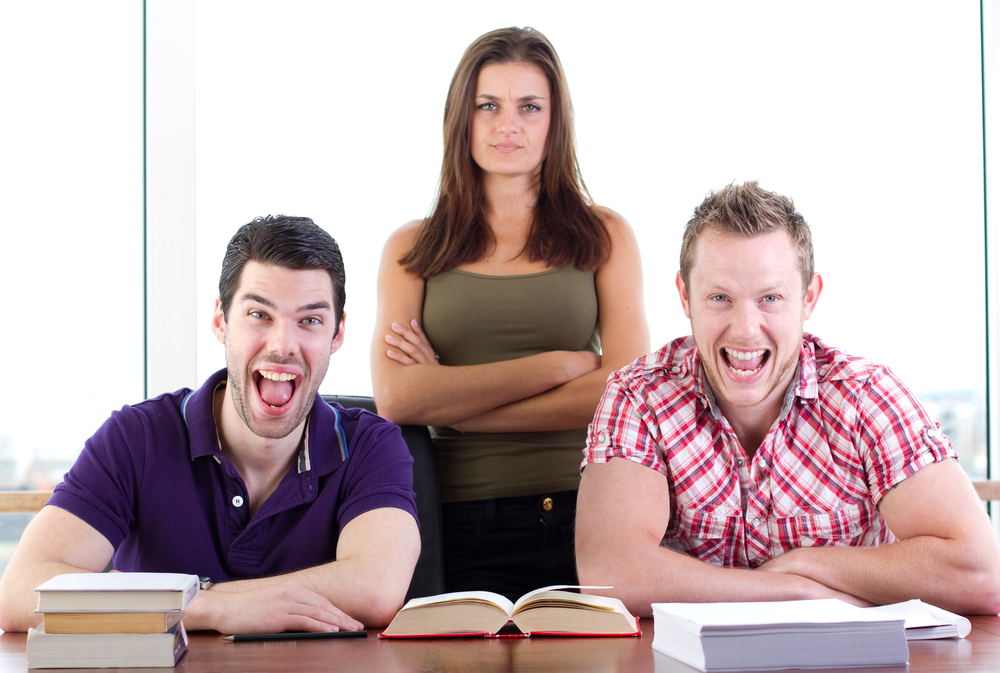 Two young male students laughing at a joke and the female behind them is not laughing