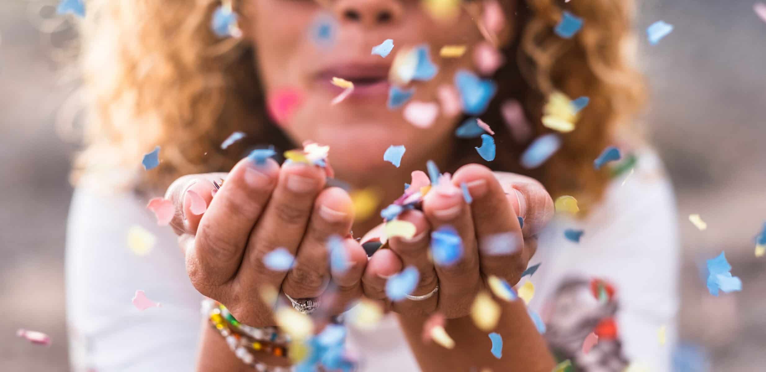 A woman blowing confetti from her hands in celebration.
