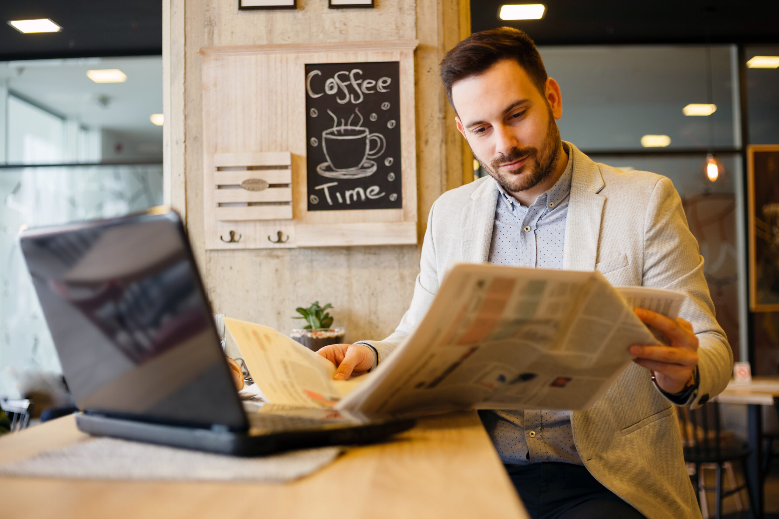 A man sitting alone in a cafe reading the newspaper.
