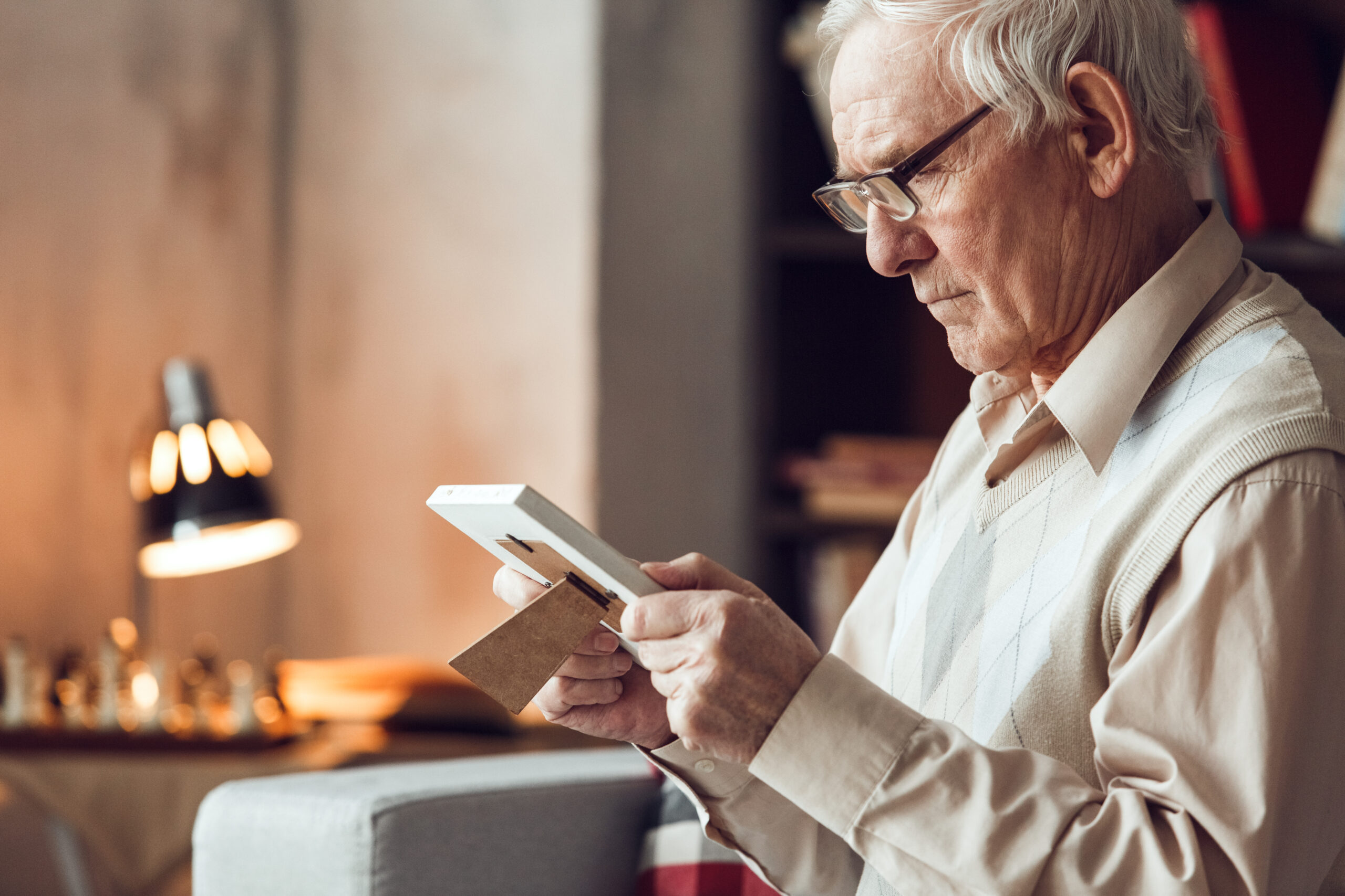 Senior man sitting alone looking at a family photo.