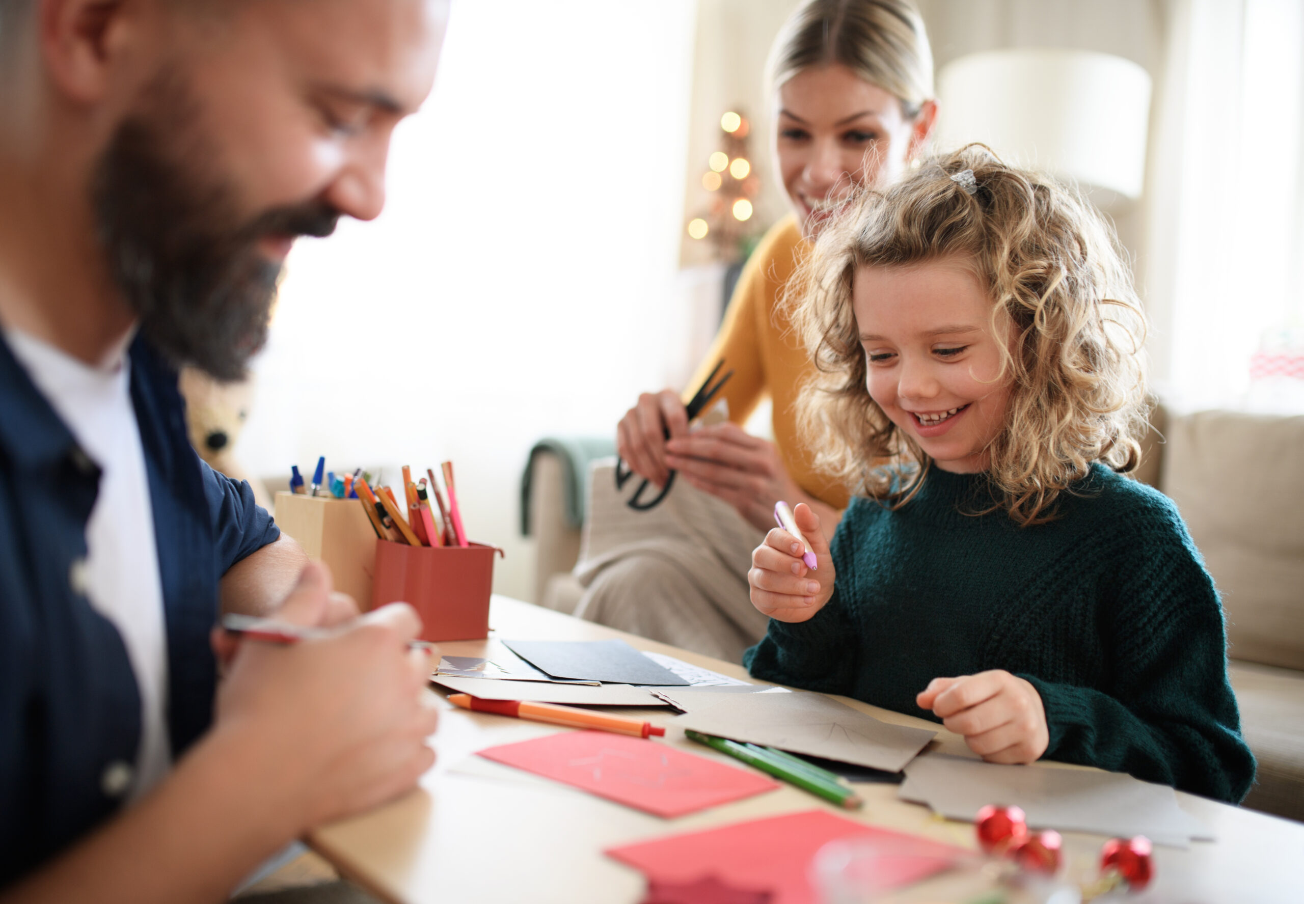 A family with small daughter writing homemade thank you cards.