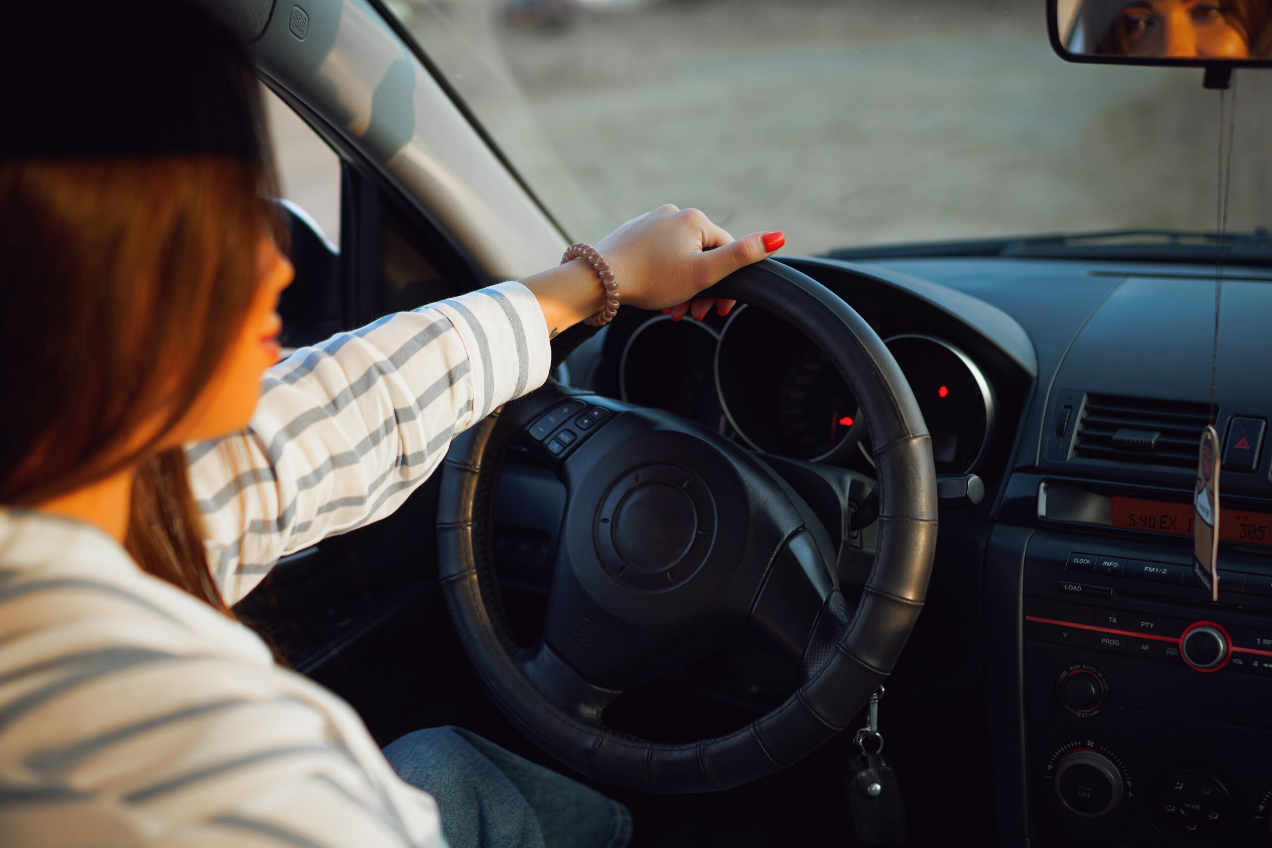 Woman driving with one hand on the steering wheel.