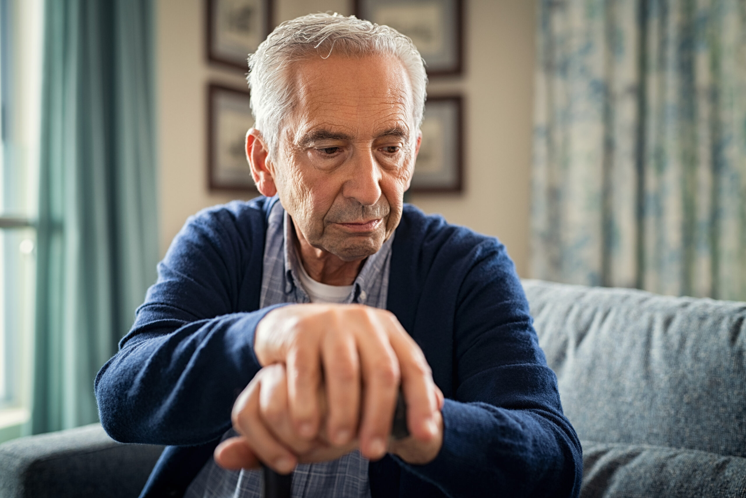 Depressed senior man sitting at home alone.