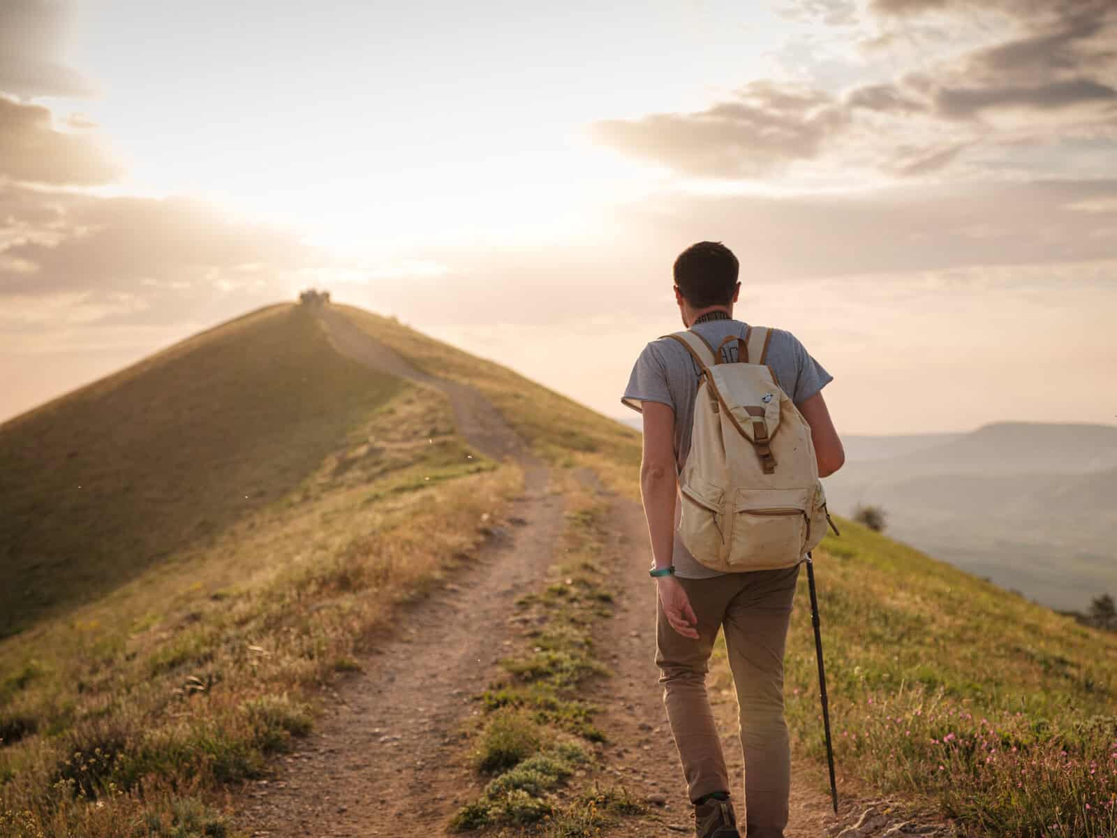 Man walking a trail alone at sunset.