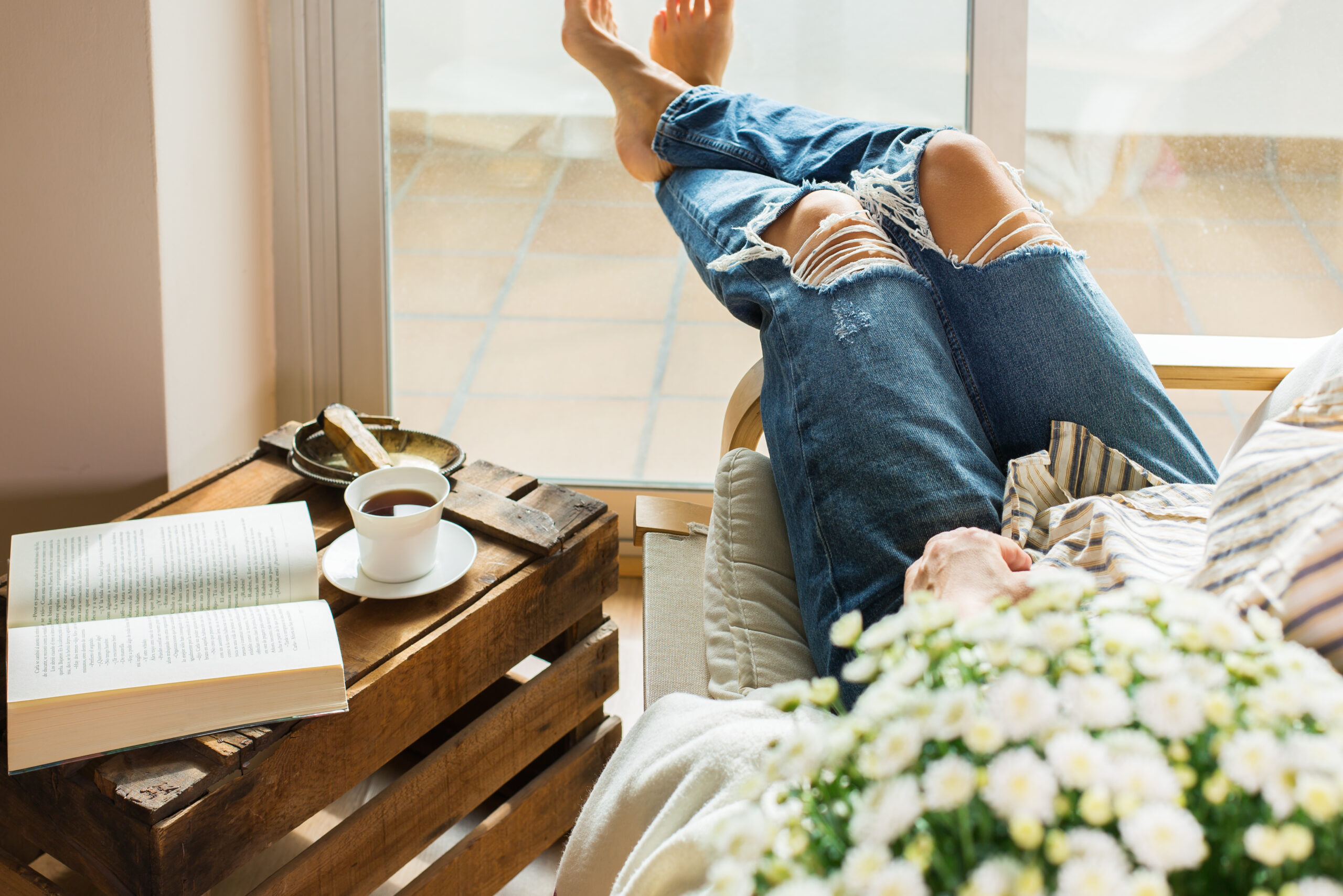 A woman relaxing at home while drinking tea and reading.