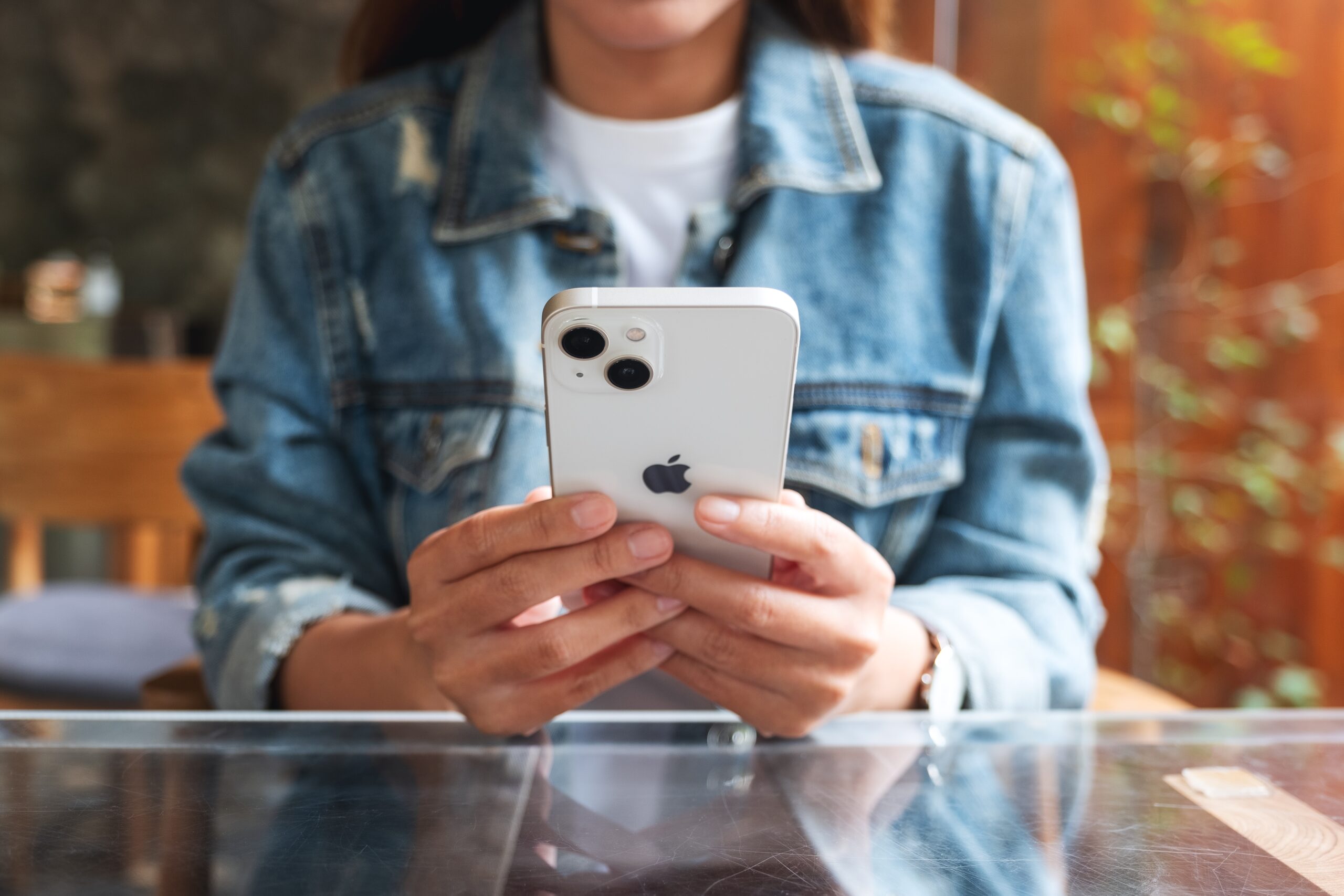 A woman sitting at her desk looking at her cell phone.