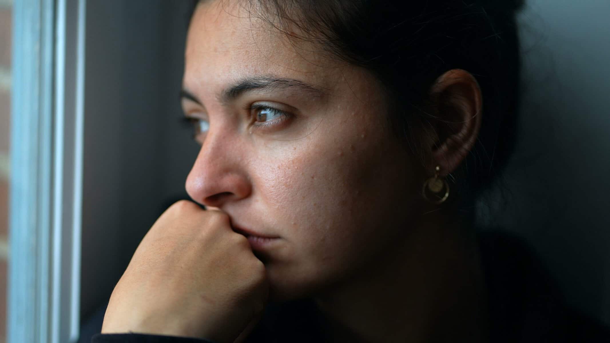 Reflective woman sitting near window.