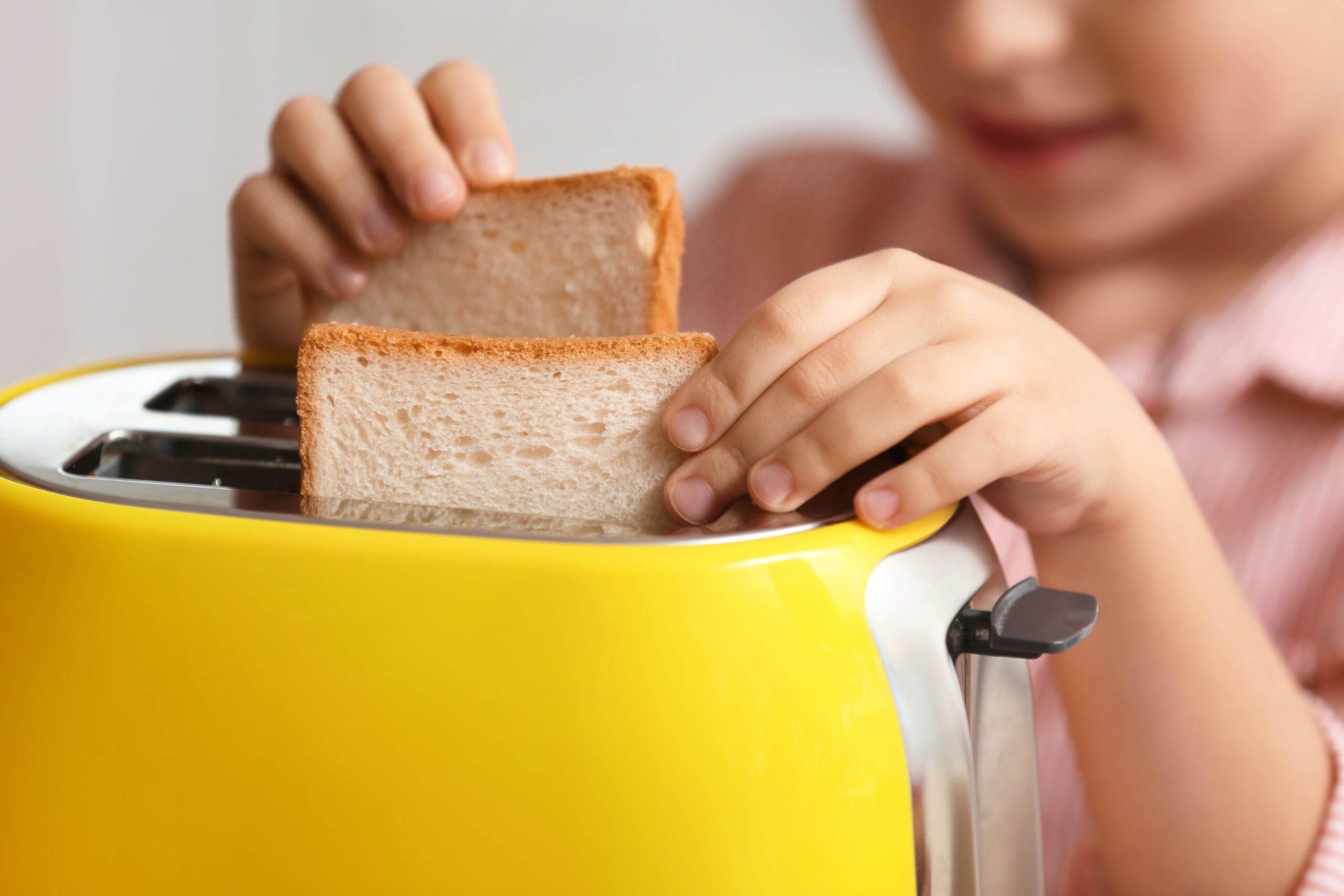 A young girl learning to toast bread.