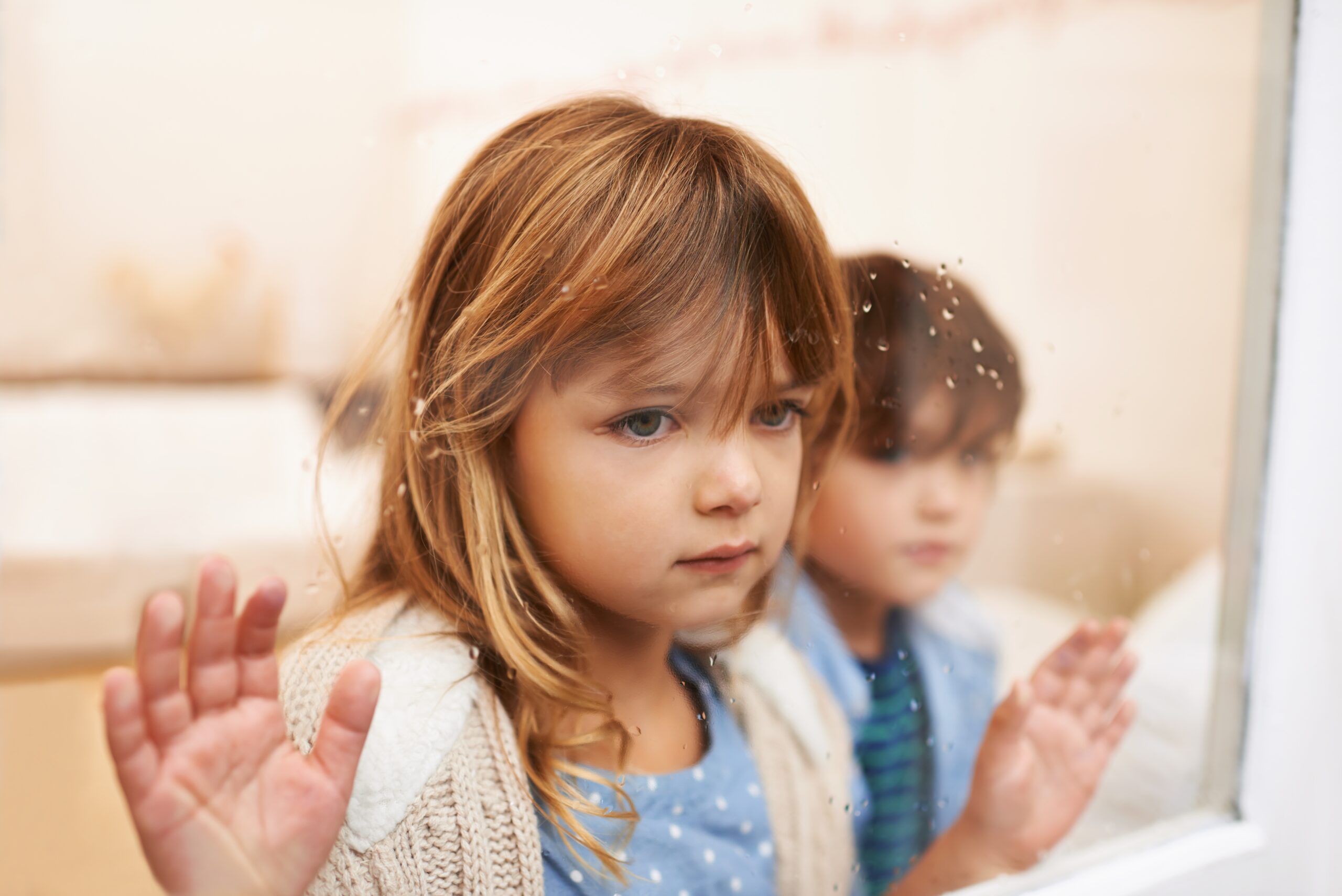 Two young children looking out the window waiting for help.